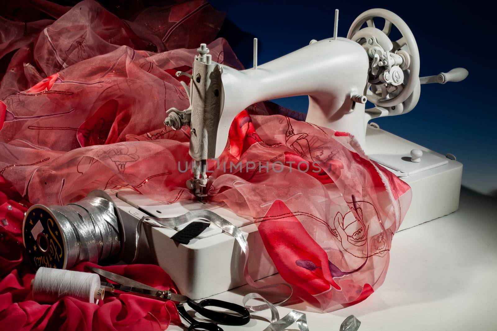 Sewing machine, fabric and scissors on a studio background