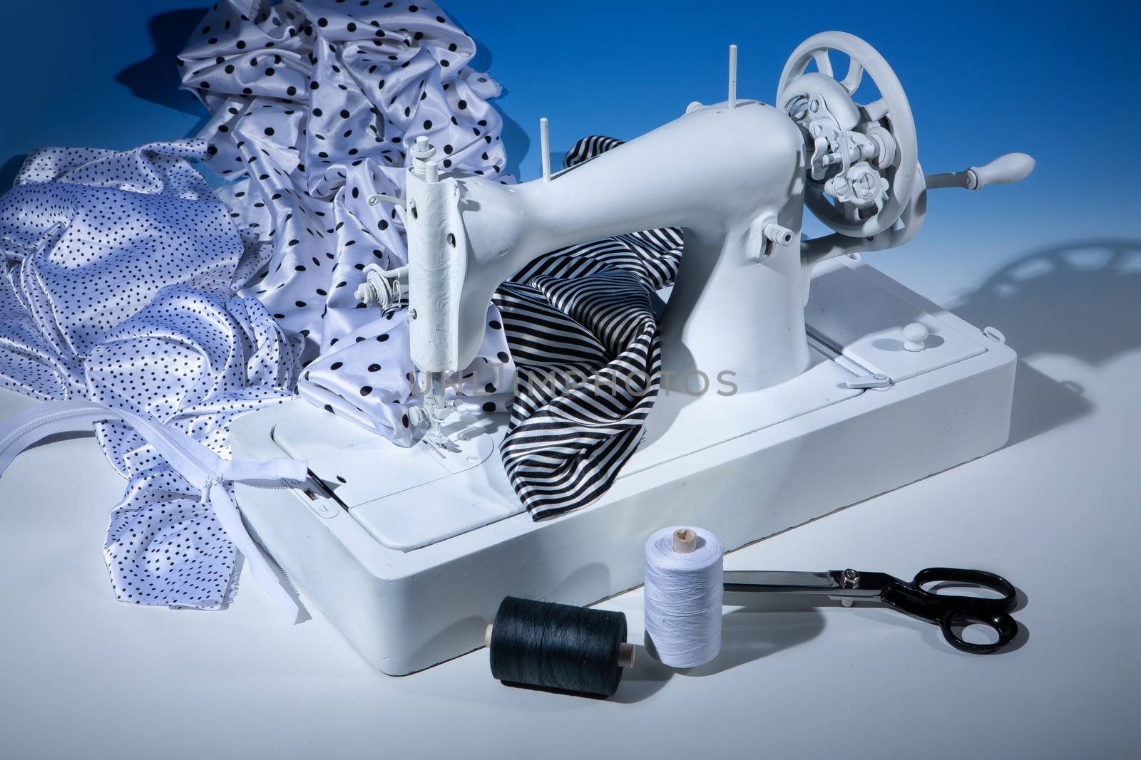 Sewing machine, fabric and scissors on a studio background