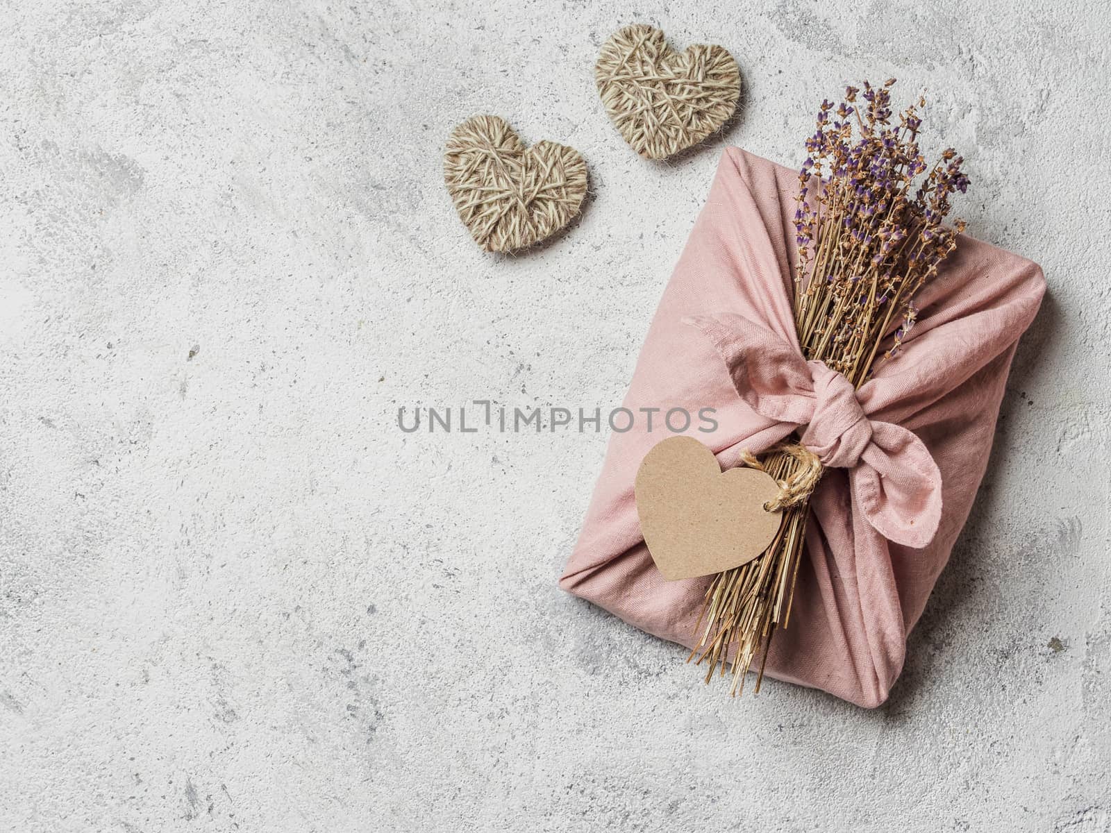 Zero waste, Valentine's Day eco-friendly gift wrapping in Furoshiki style with dry lavender. Gift box in cloth wrapping, on gray background. Copy space for text. Top view, flat lay