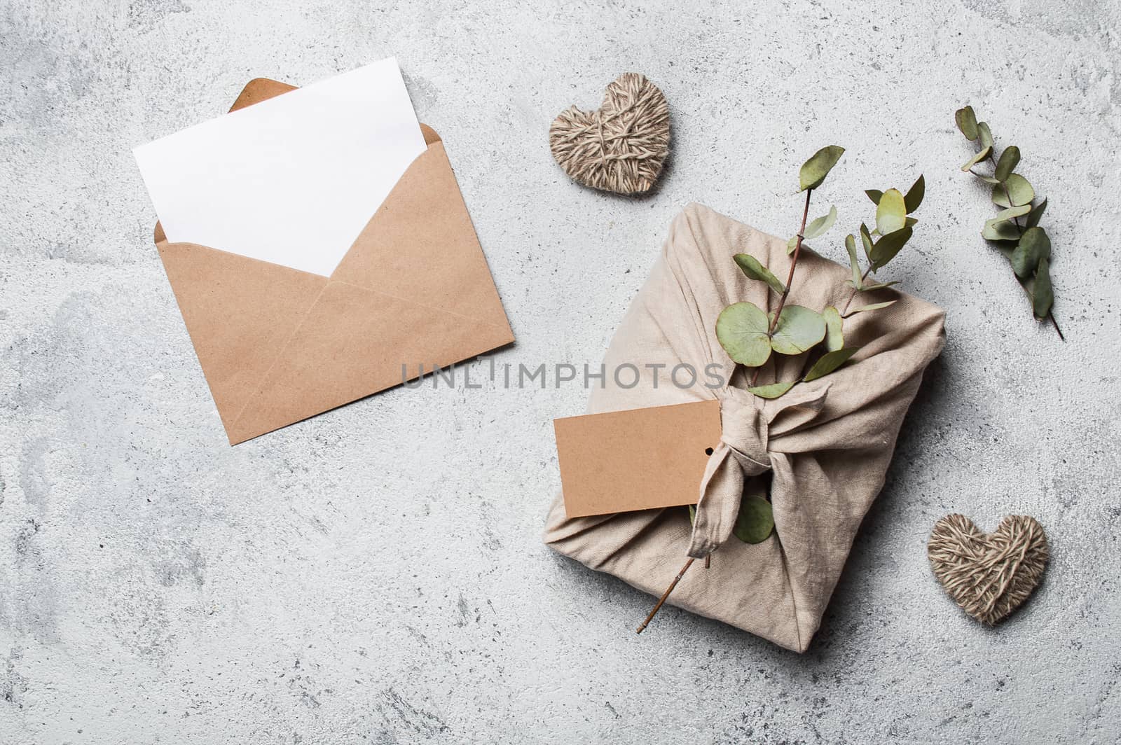 Zero waste Valentine's Day concept and mock up. Eco-friendly gift cloth wrapping in Furoshiki style, craft paper envelope,empty gift or greetings card. Top down view or flat lay. Copy space for design