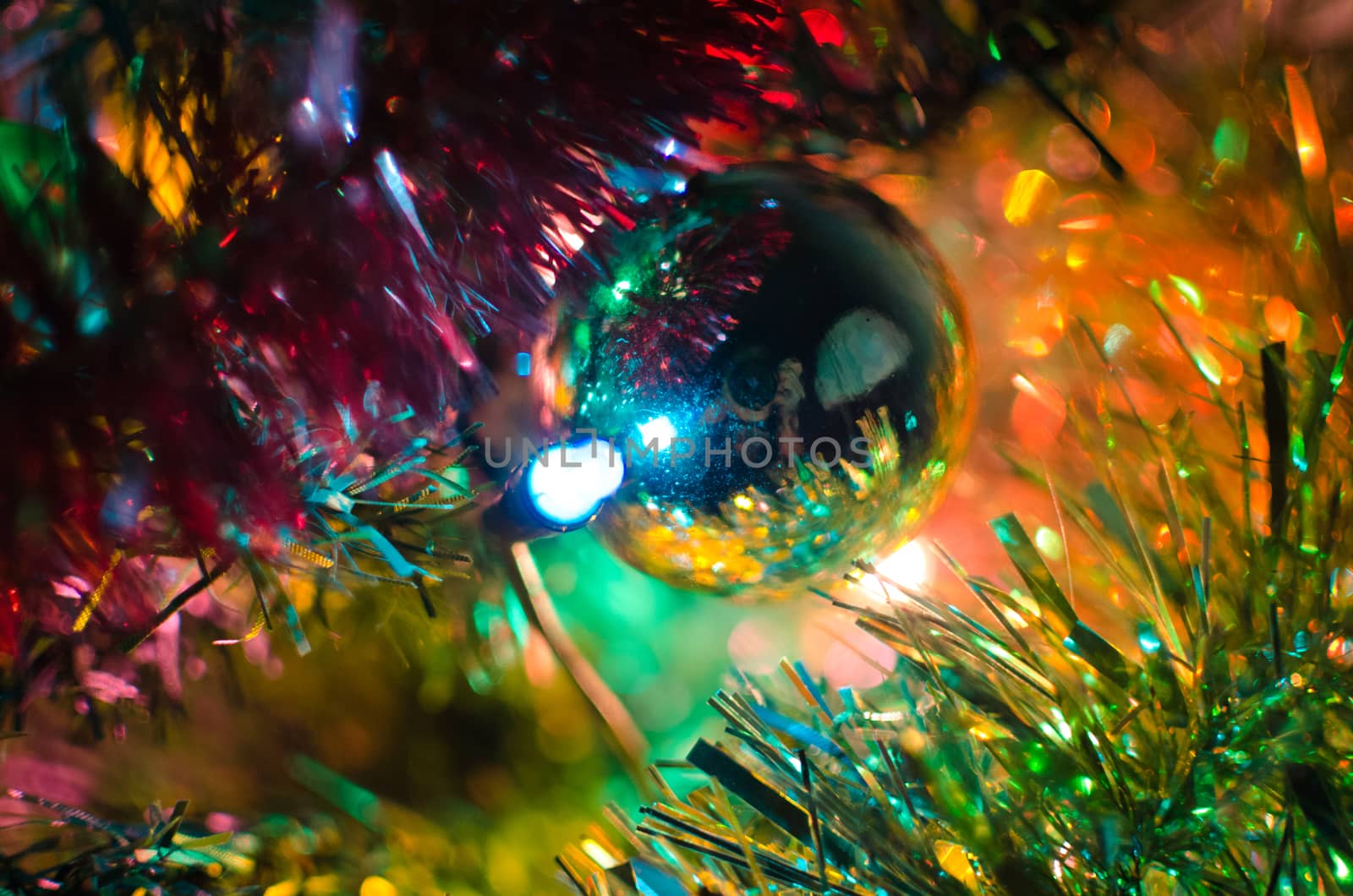 Photographers reflexion over a Christmas tree ball surrounded by colorful spumillion