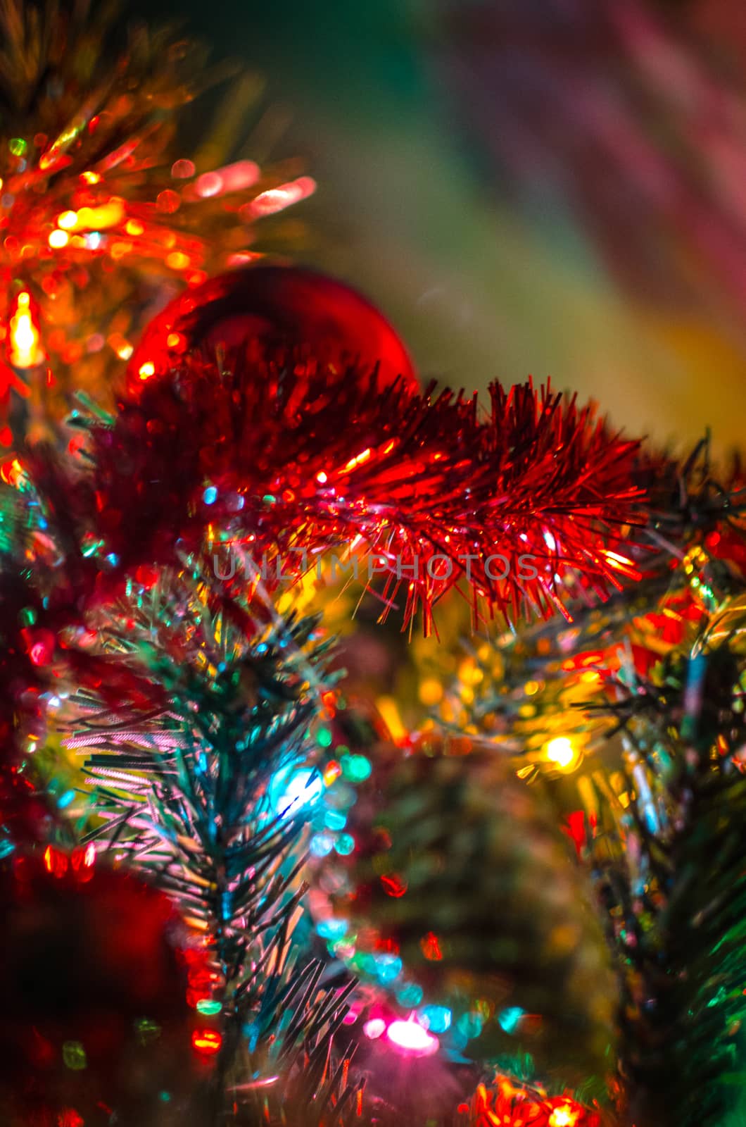 Detail of a Christmas tree where a red ball, a golden pinecone and spumillion provide a colorful scene