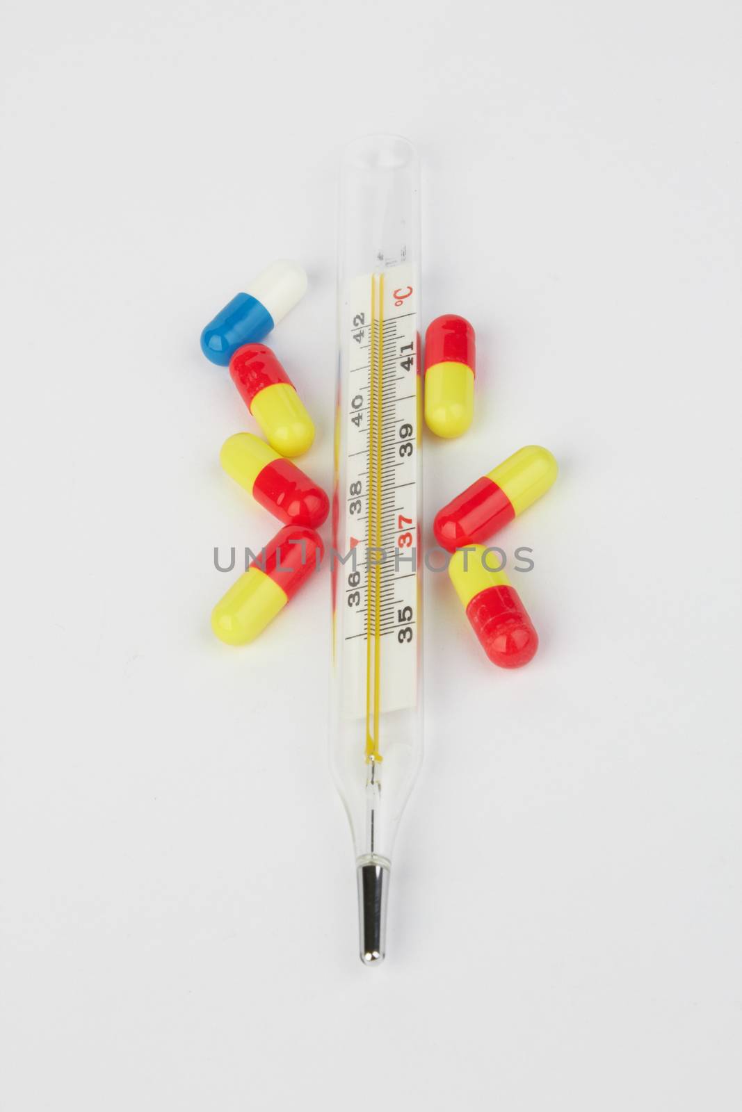 Thermometer and pills on white