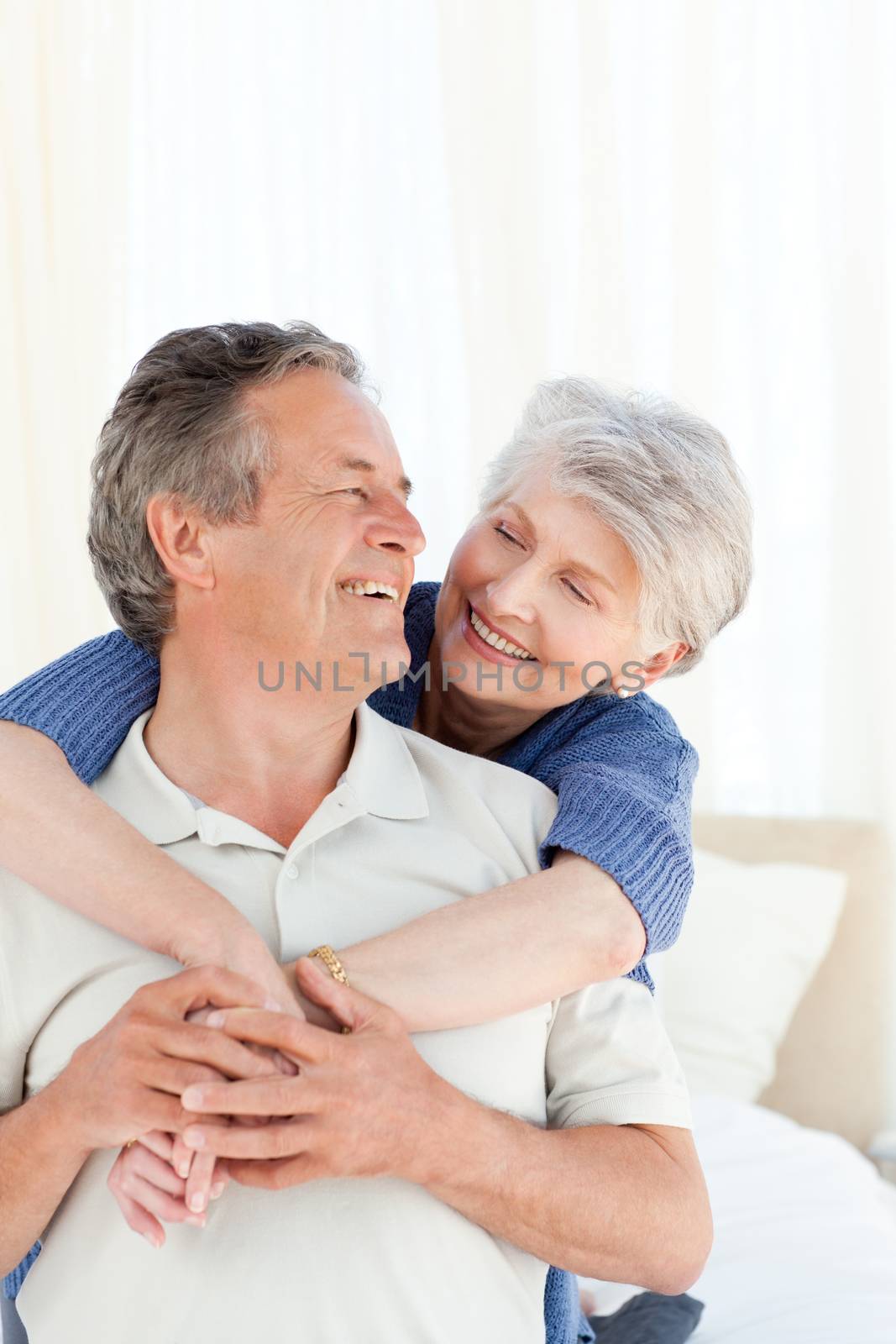 Senior couple hugging on their bed at home