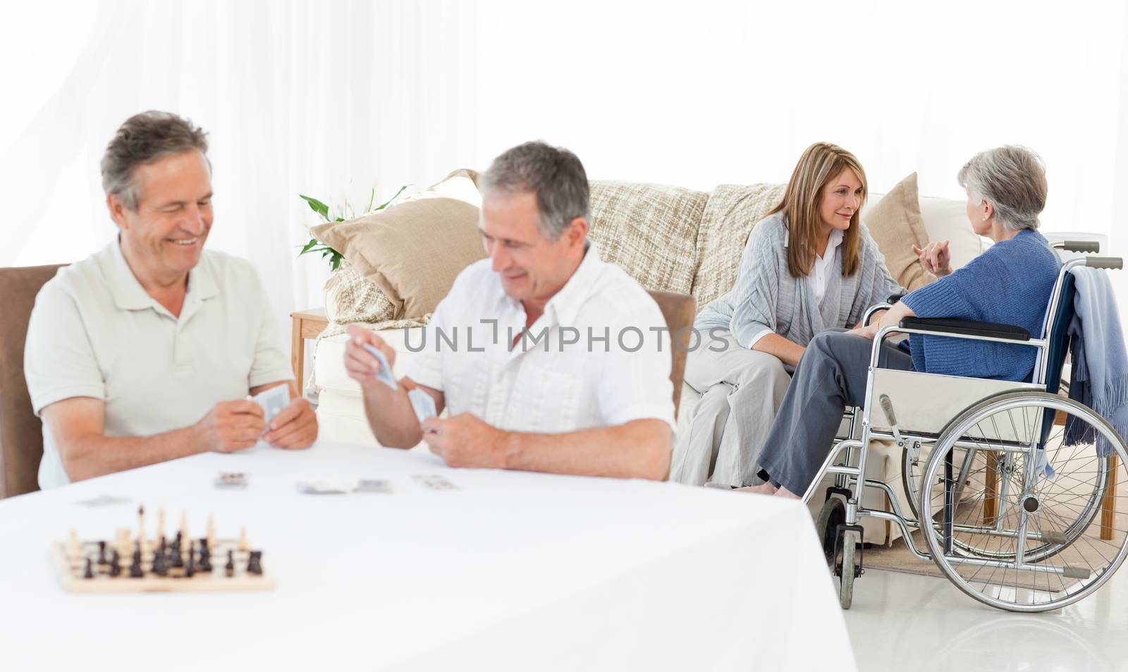 Men playing cards while their wifes are talking