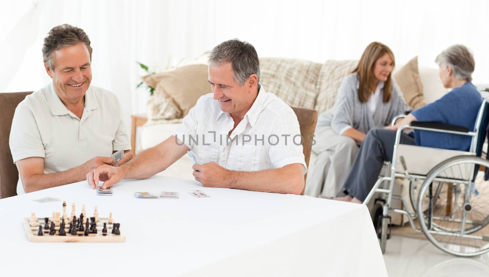 Men playing cards while their wifes are talking