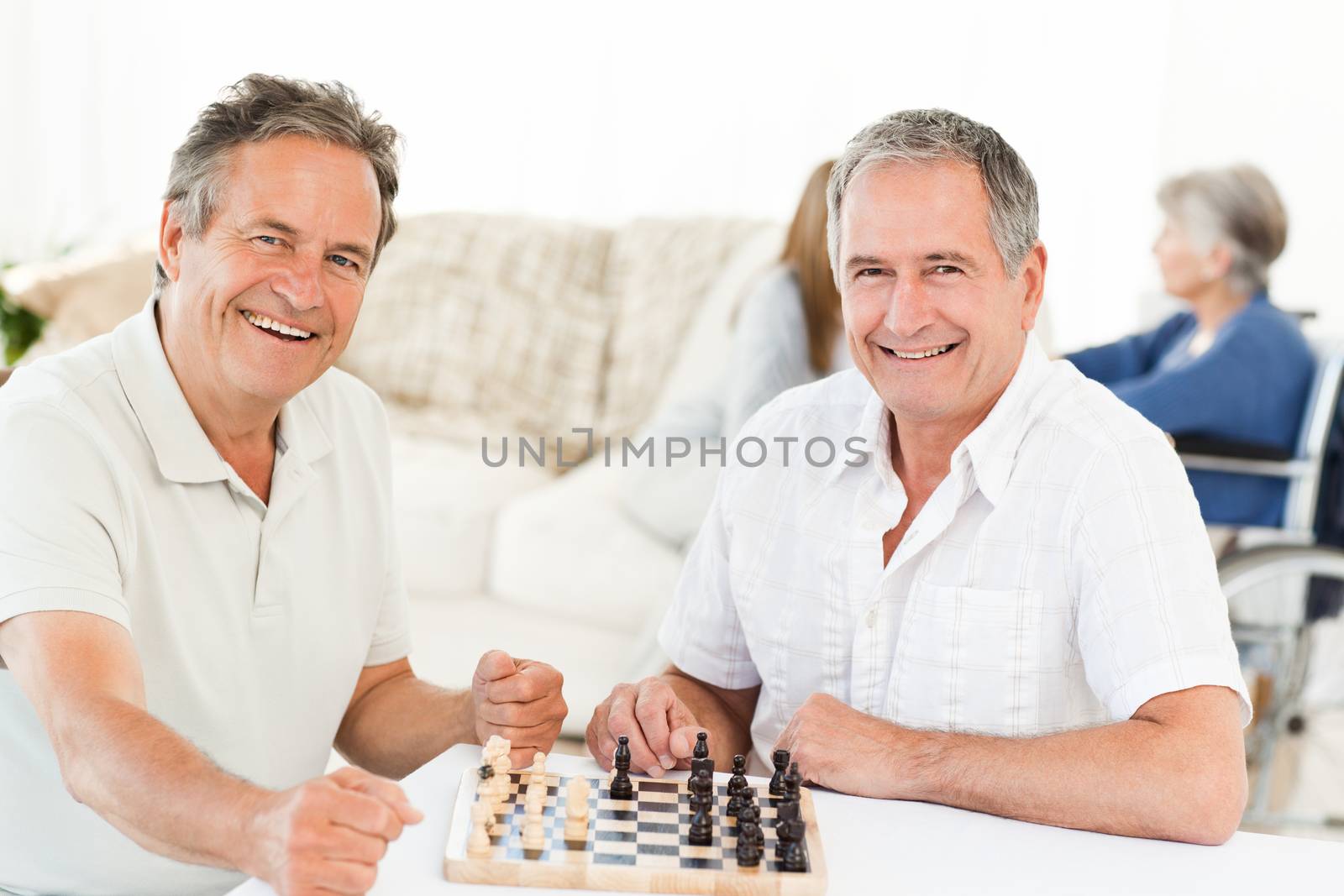 Men playing chess while their wifes are talking by Wavebreakmedia