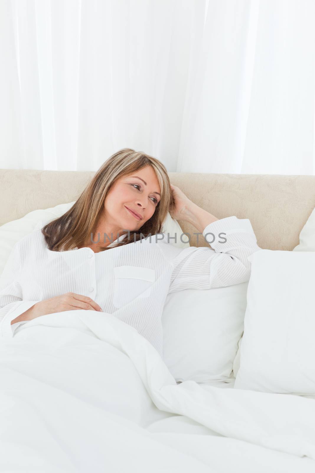 Mature woman lying down in her bed at home