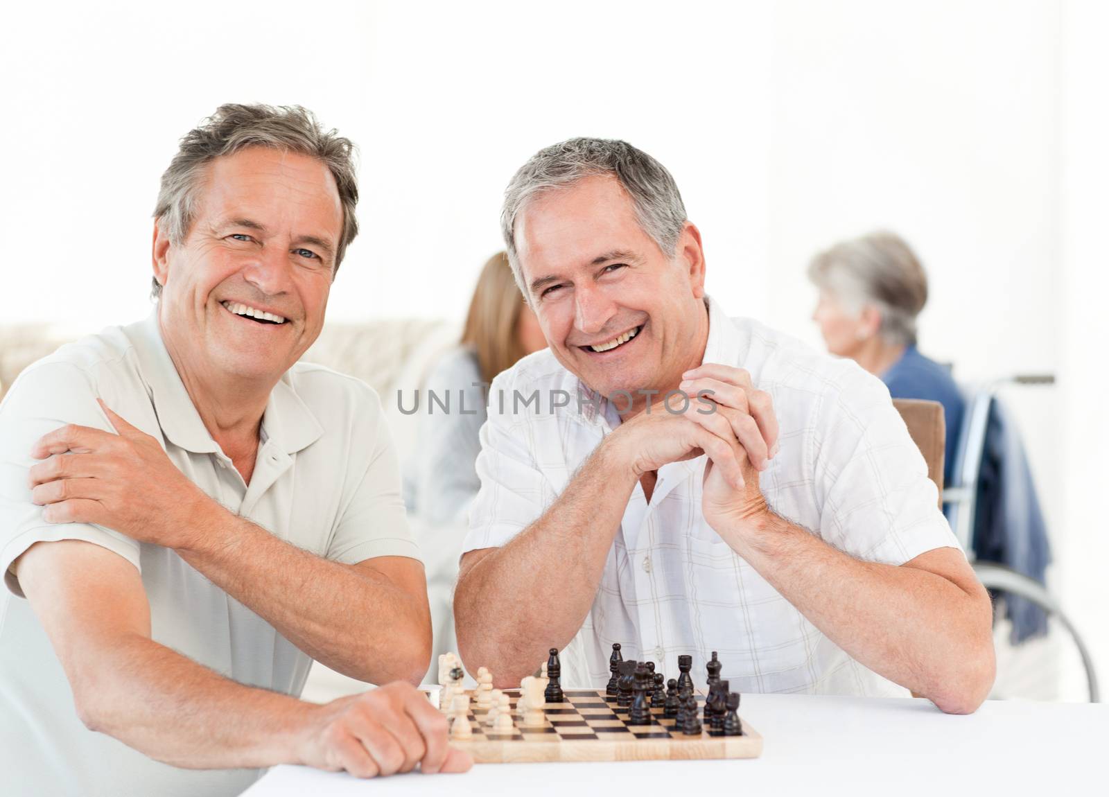 Men playing chess while their wifes are talking by Wavebreakmedia