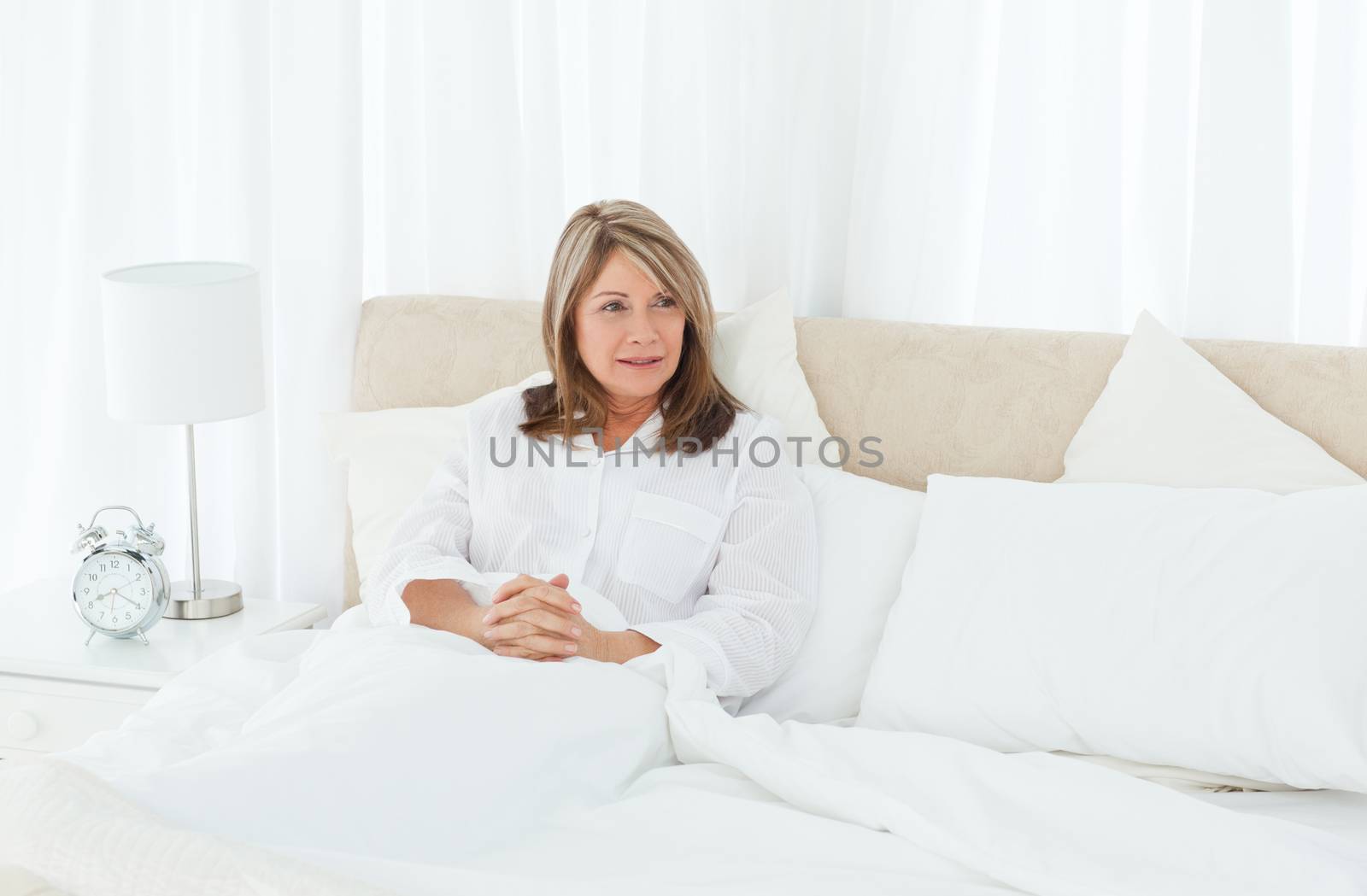 Mature woman lying down in her bed by Wavebreakmedia