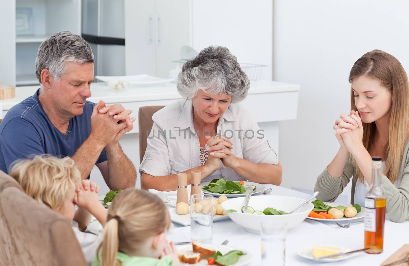 Family praying at the table by Wavebreakmedia