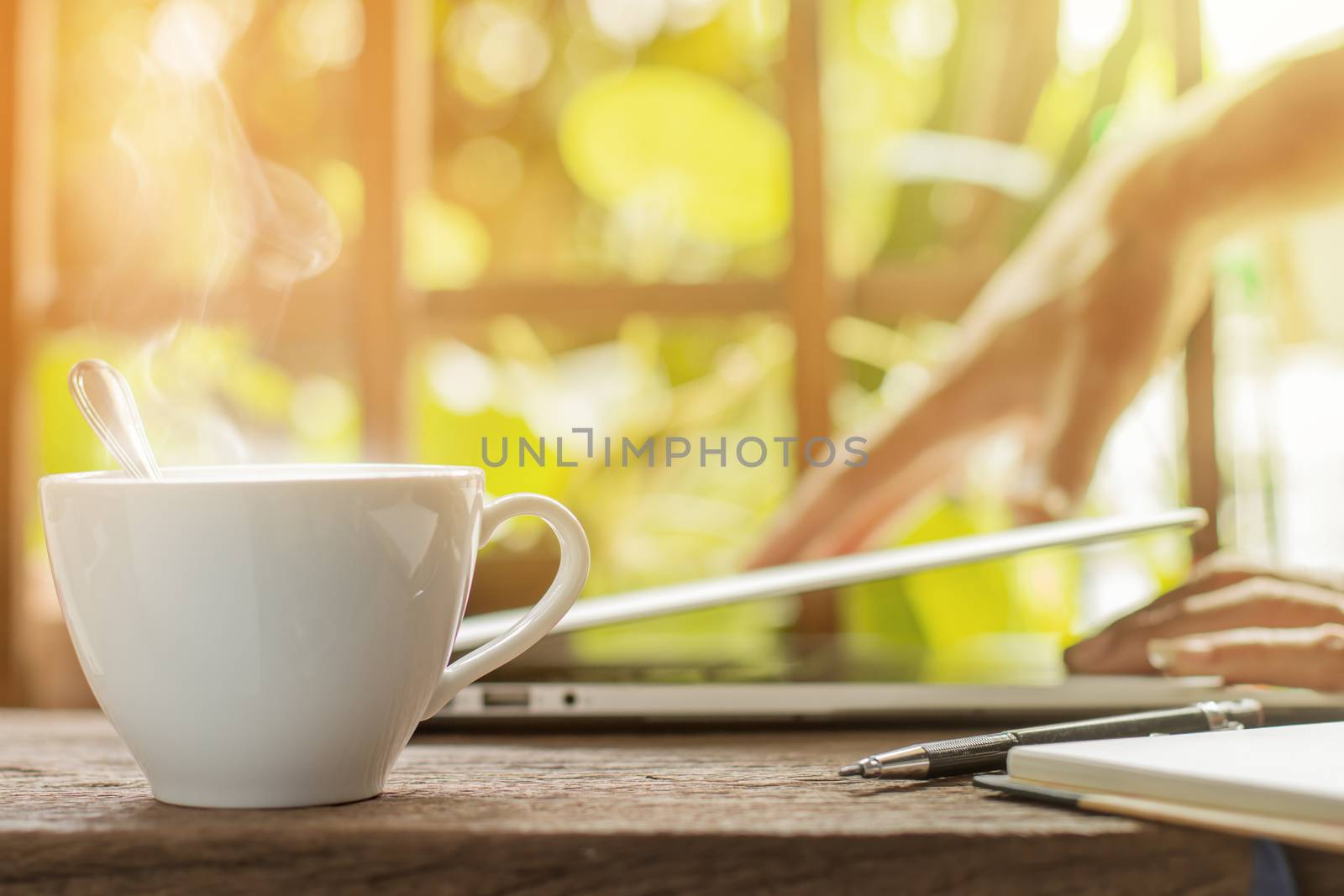 White hot coffee cup with businessman closing laptop green garden background