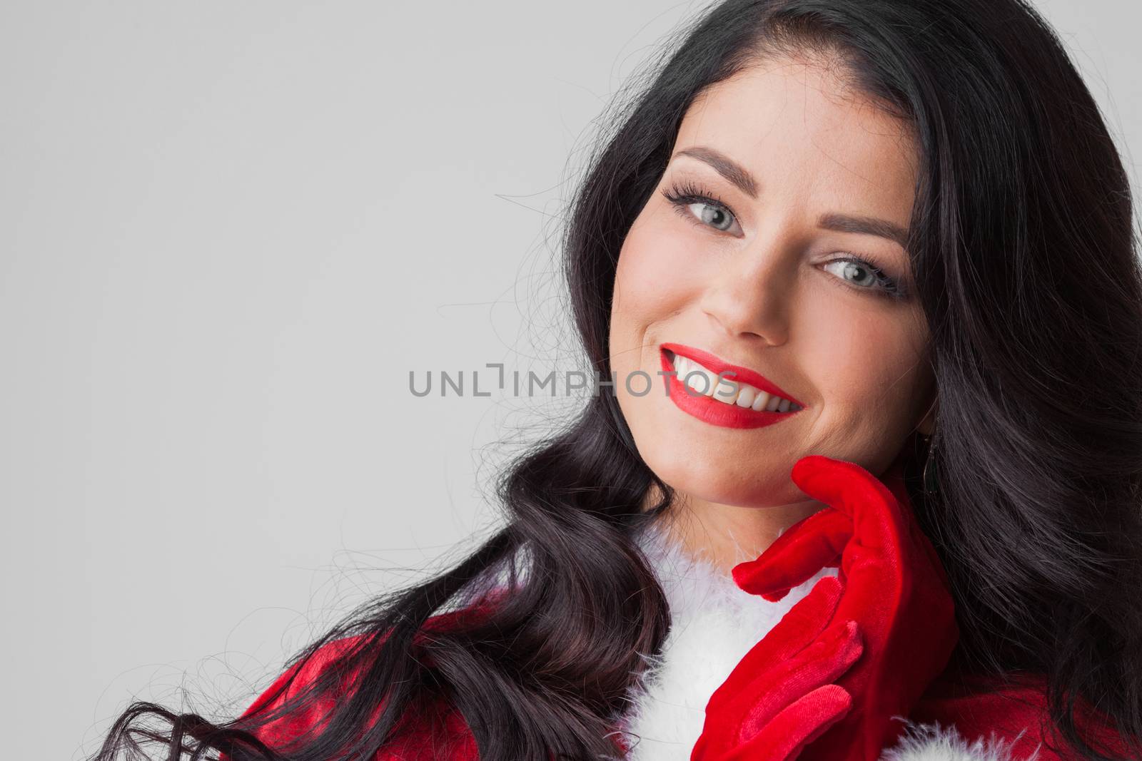 Pretty Pin-up style Santa girl in red clothes on gray background