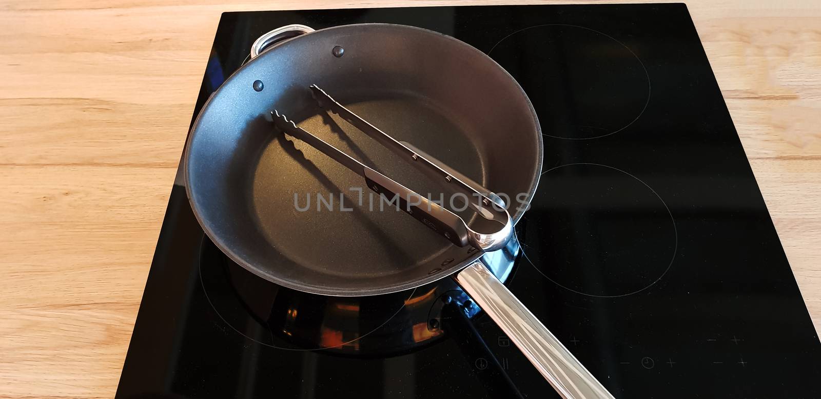Pan on modern black induction stove, stove, hob with ceramic plate in dark kitchen interior