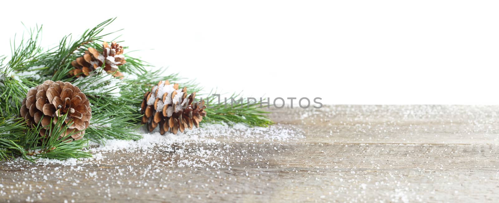 Christmas card. Pine cone and green branch on wooden table with snow, copy space for text, isolated on white background