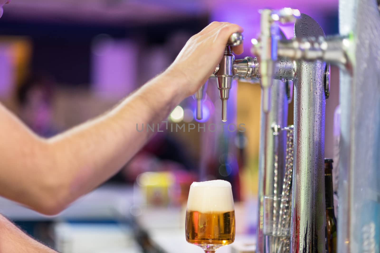 Bartender pouring lager beer in a glass. Shallow dof, selective focus.