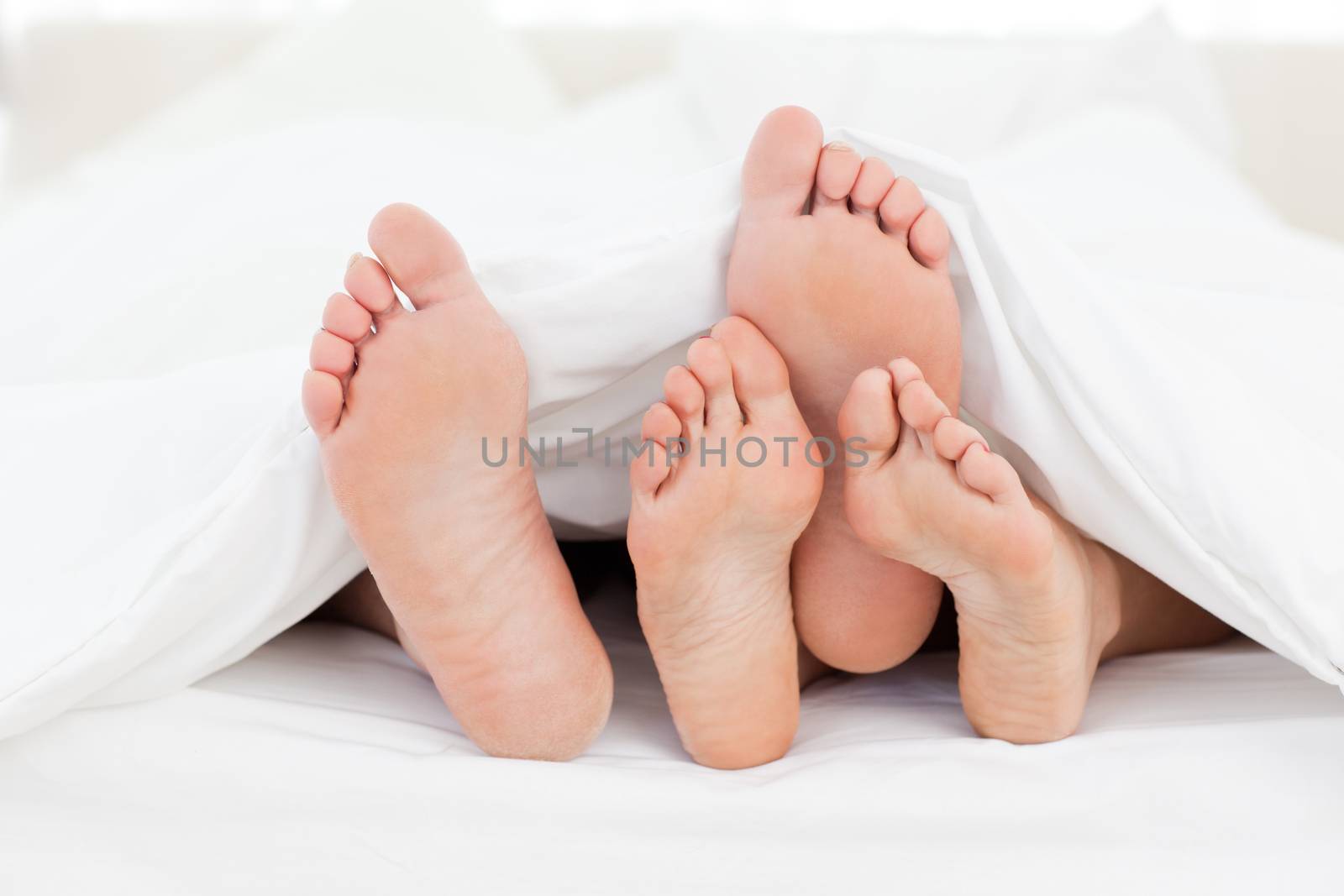 Two members of a family showing their feet while lying on a bed