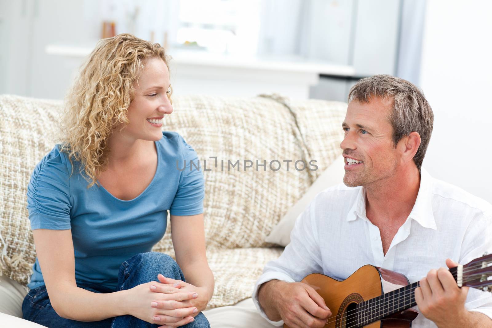 Romantic man playing guitar for her wife at home by Wavebreakmedia