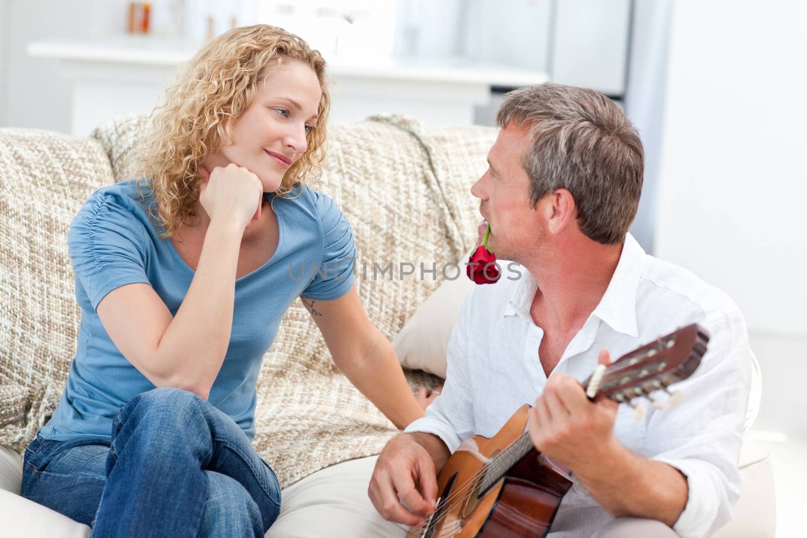 Romantic man playing guitar for her wife at home by Wavebreakmedia