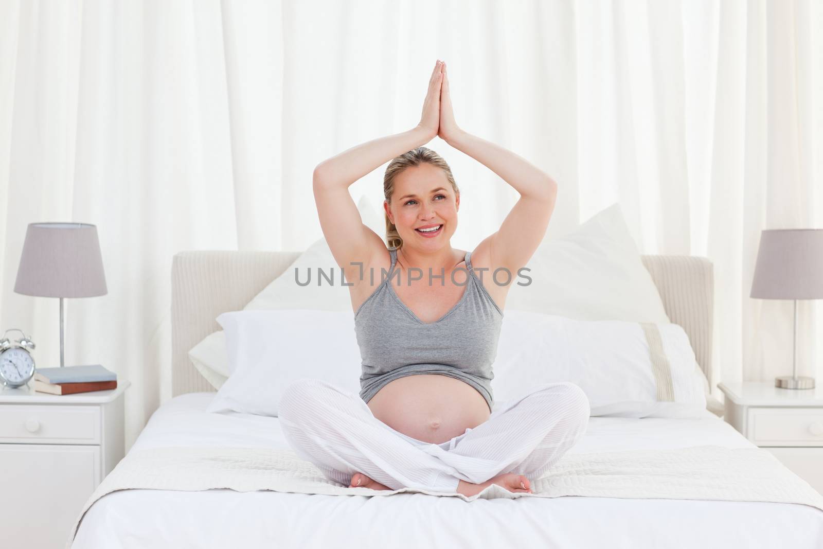 Pregnant woman practicing yoga on her bed by Wavebreakmedia