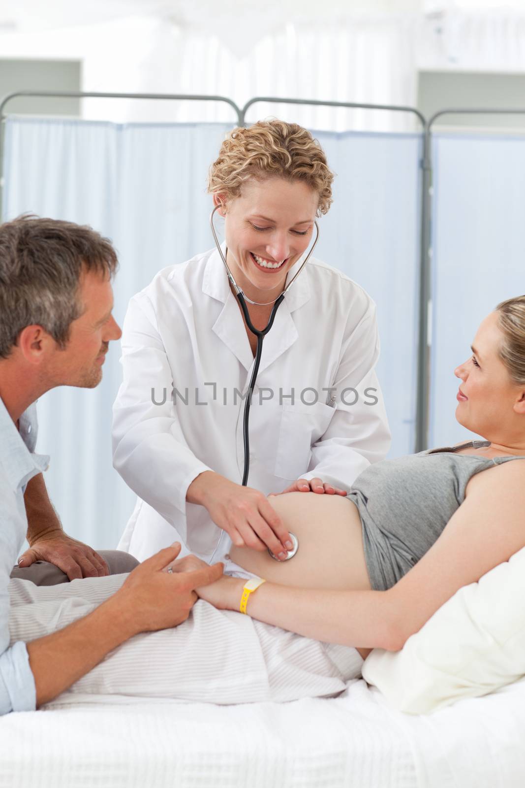 Pregnant woman with her husband listening to the nurse by Wavebreakmedia