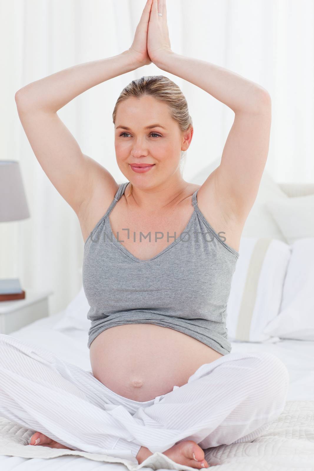 Pregnant woman practicing yoga on her bed by Wavebreakmedia