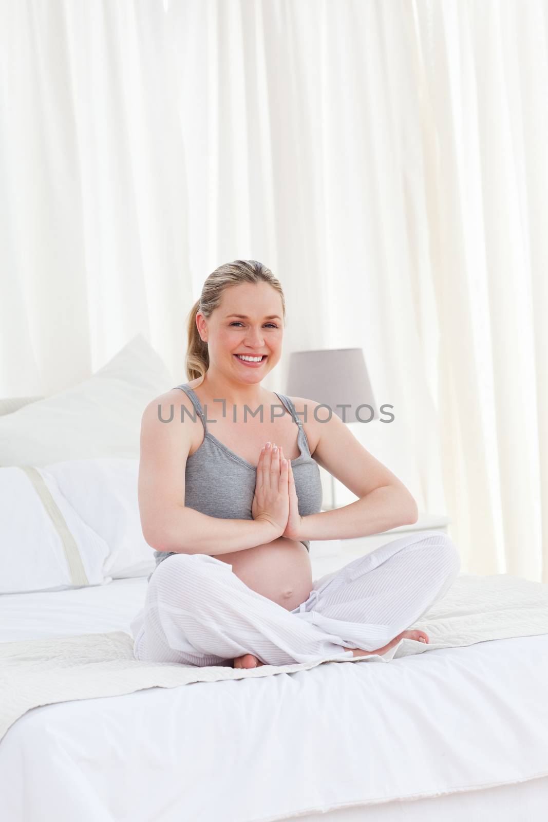 Pregnant woman practicing yoga on her bed