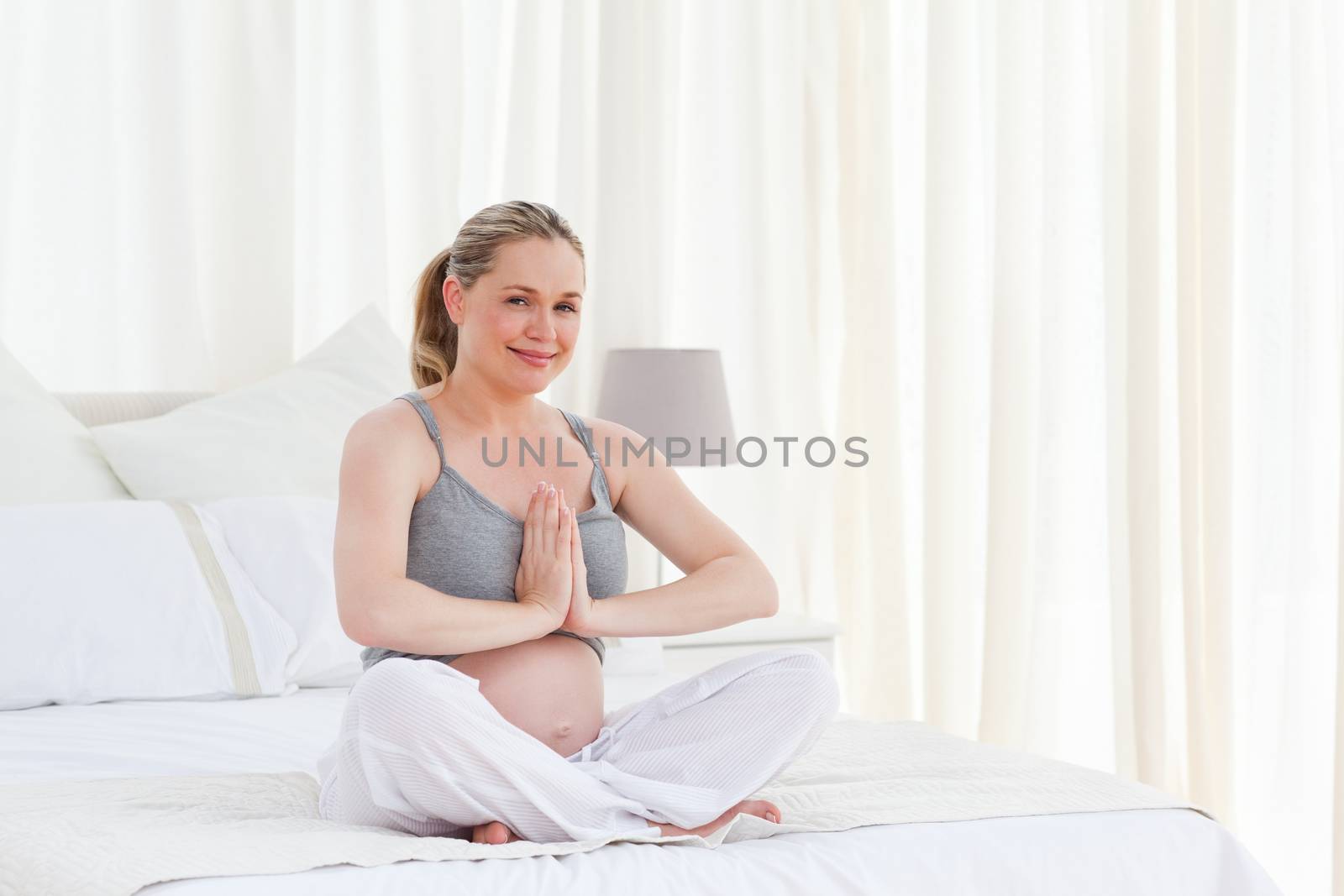 Pregnant woman practicing yoga on her bed by Wavebreakmedia