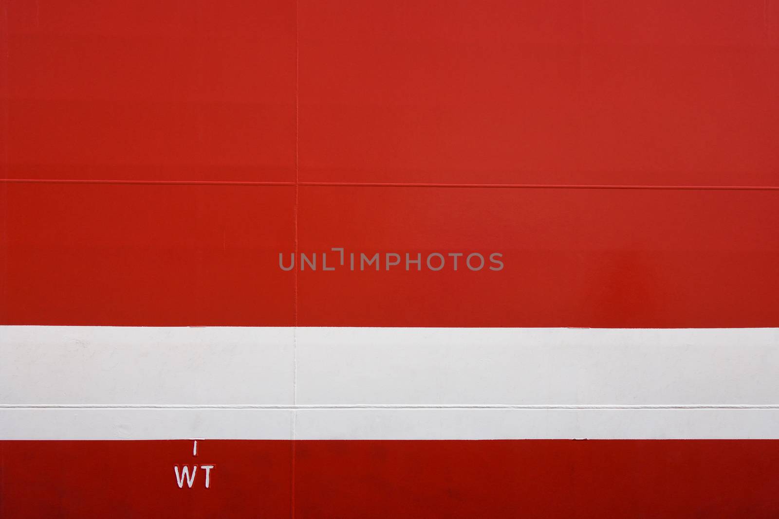 Metal hull of a large red ship with horizontal white weight load line, Cape Town, South Africa