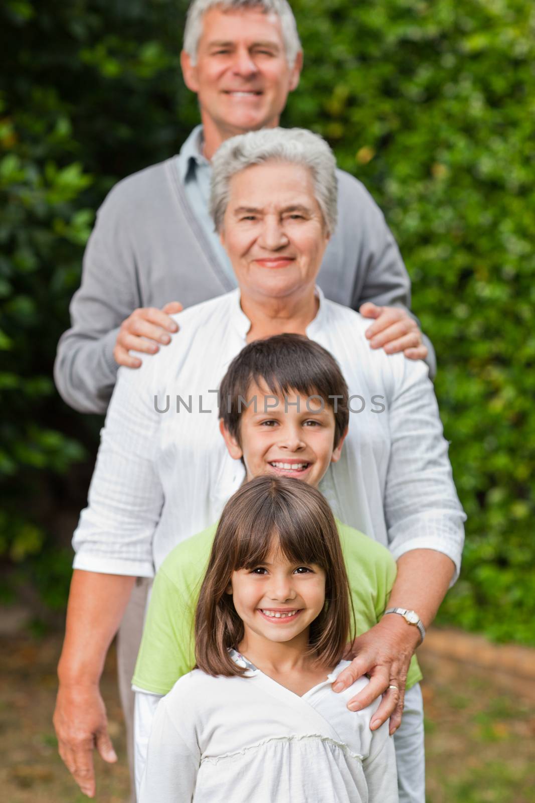 Grandparents with their children looking at the camera in the garden by Wavebreakmedia