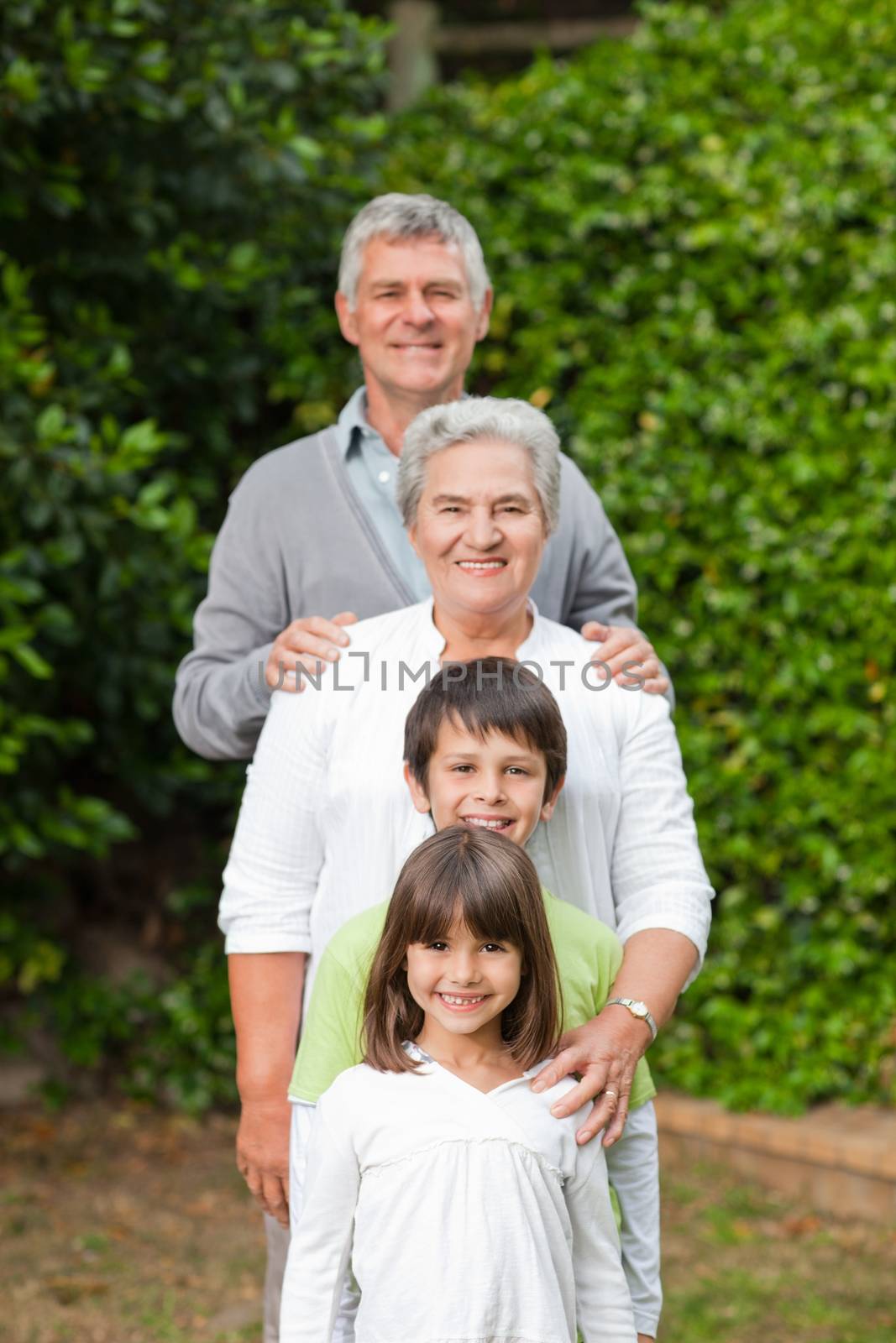 Grandparents with their children looking at the camera in the garden