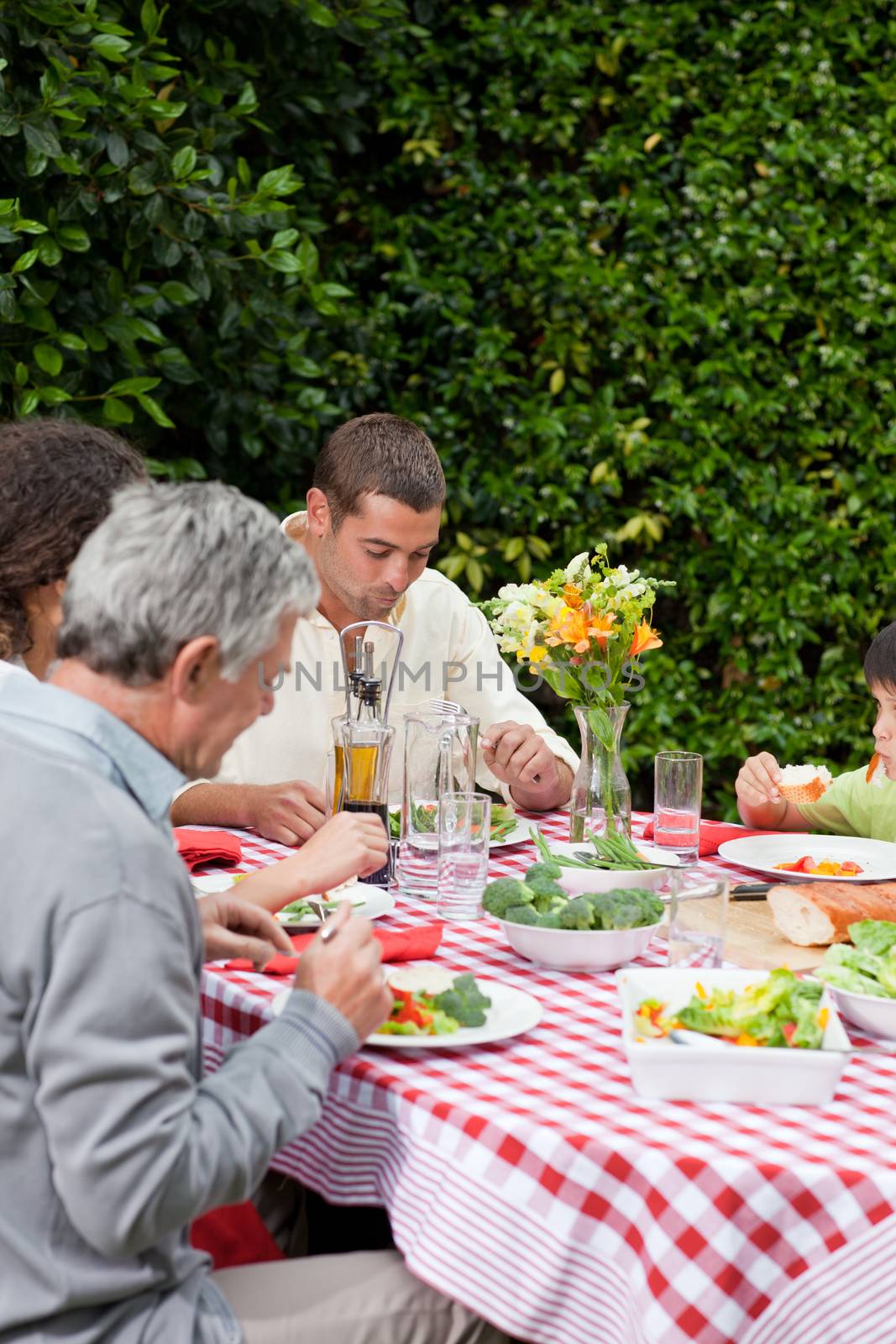 Happy family eating in the garden by Wavebreakmedia