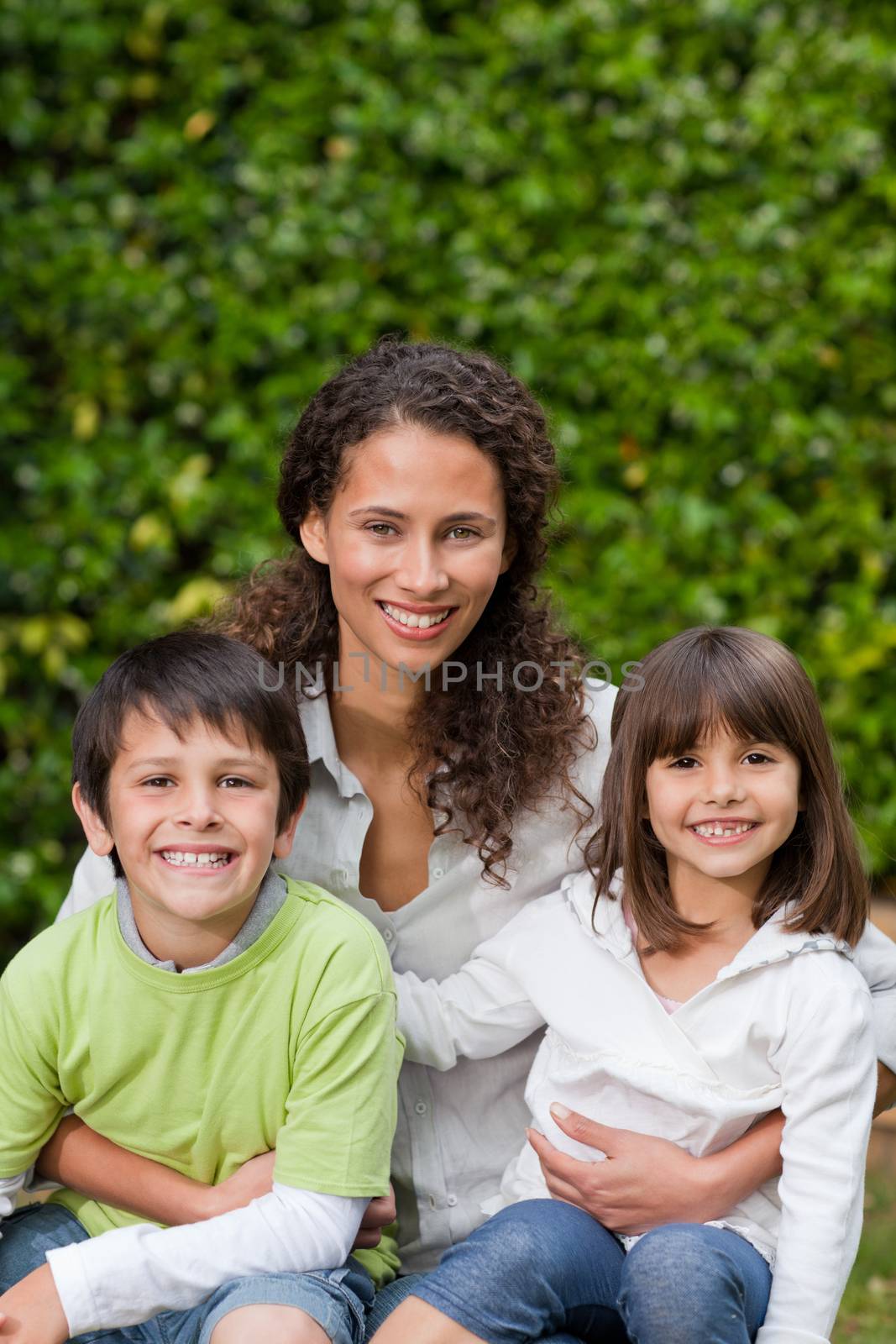 Mother with their children looking at the camera in the garden by Wavebreakmedia