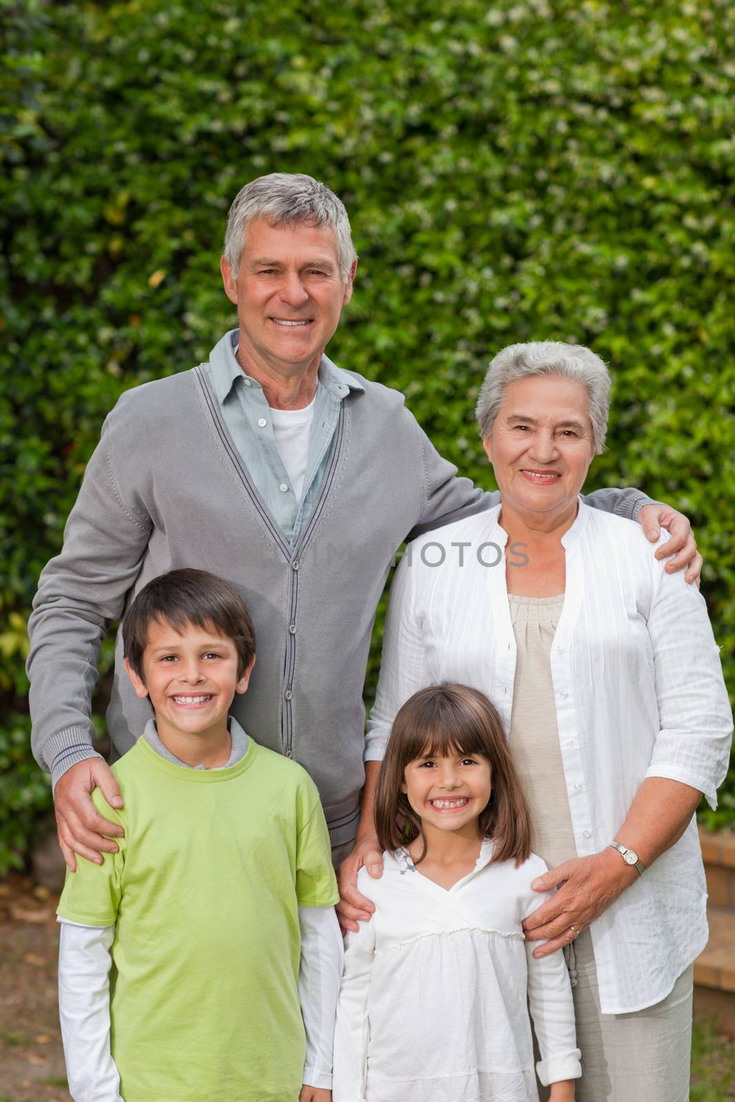 Grandparents with their children looking at the camera in the garden by Wavebreakmedia