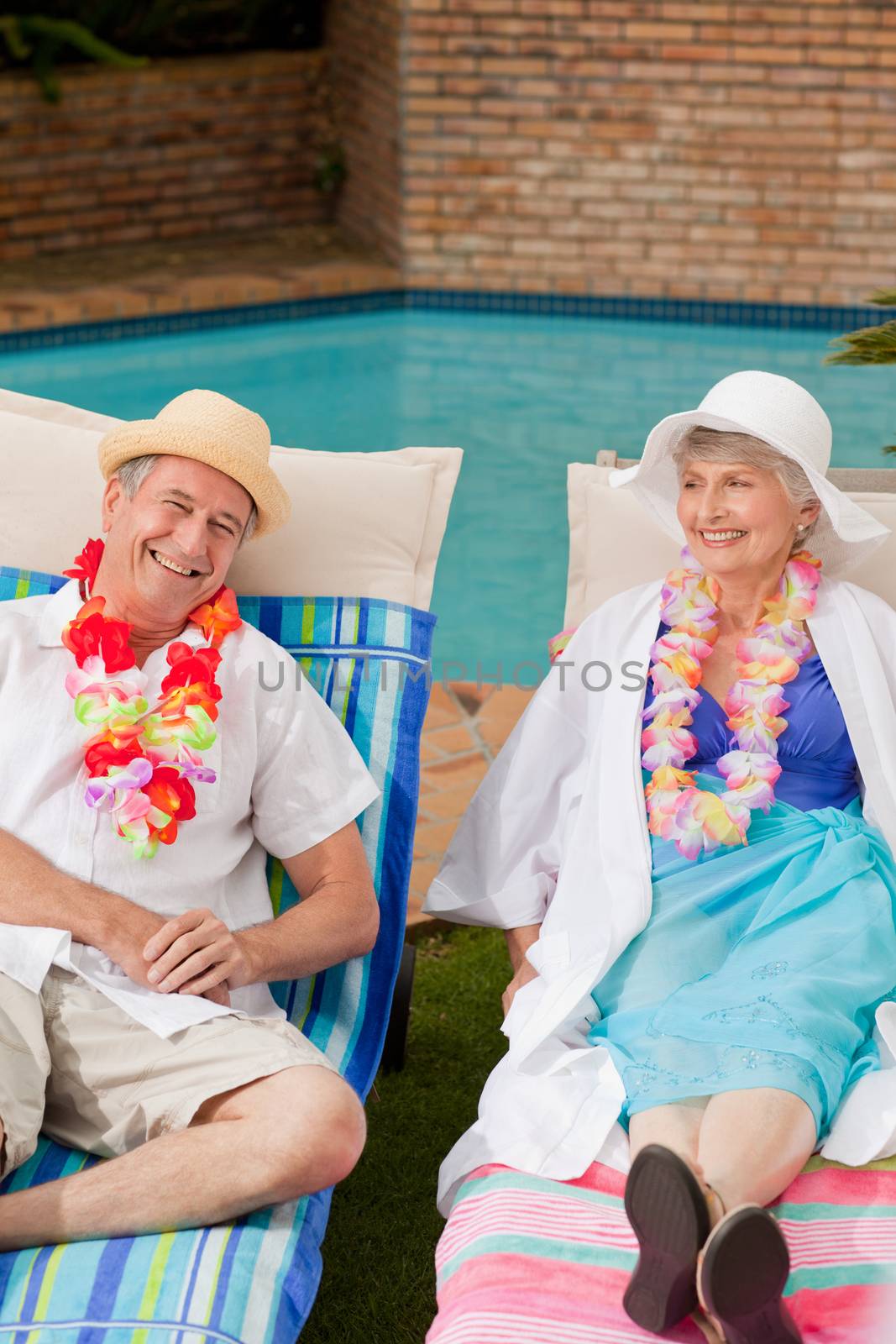 Senior couple lying down beside the swimming pool