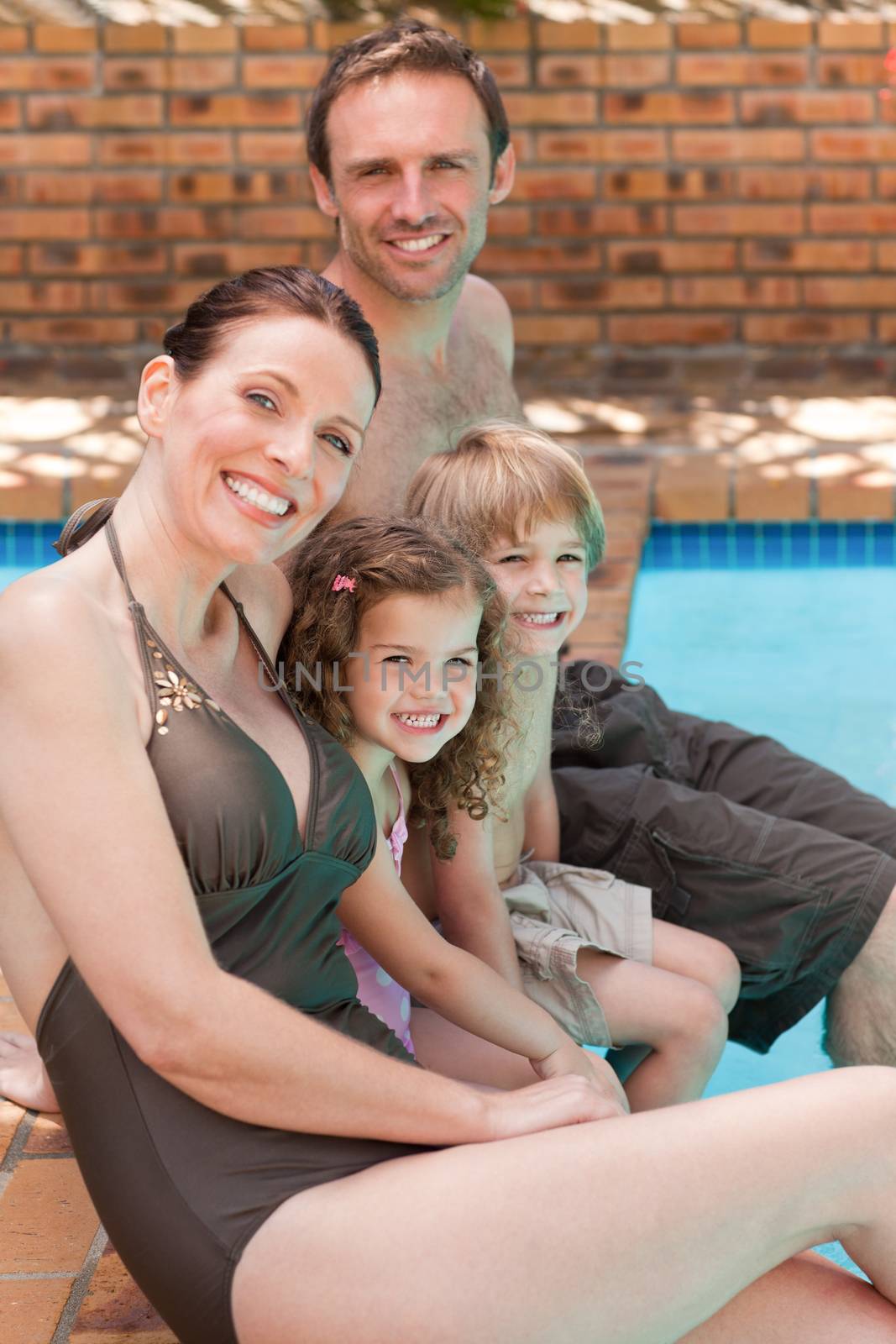 Happy family beside the swimming pool by Wavebreakmedia