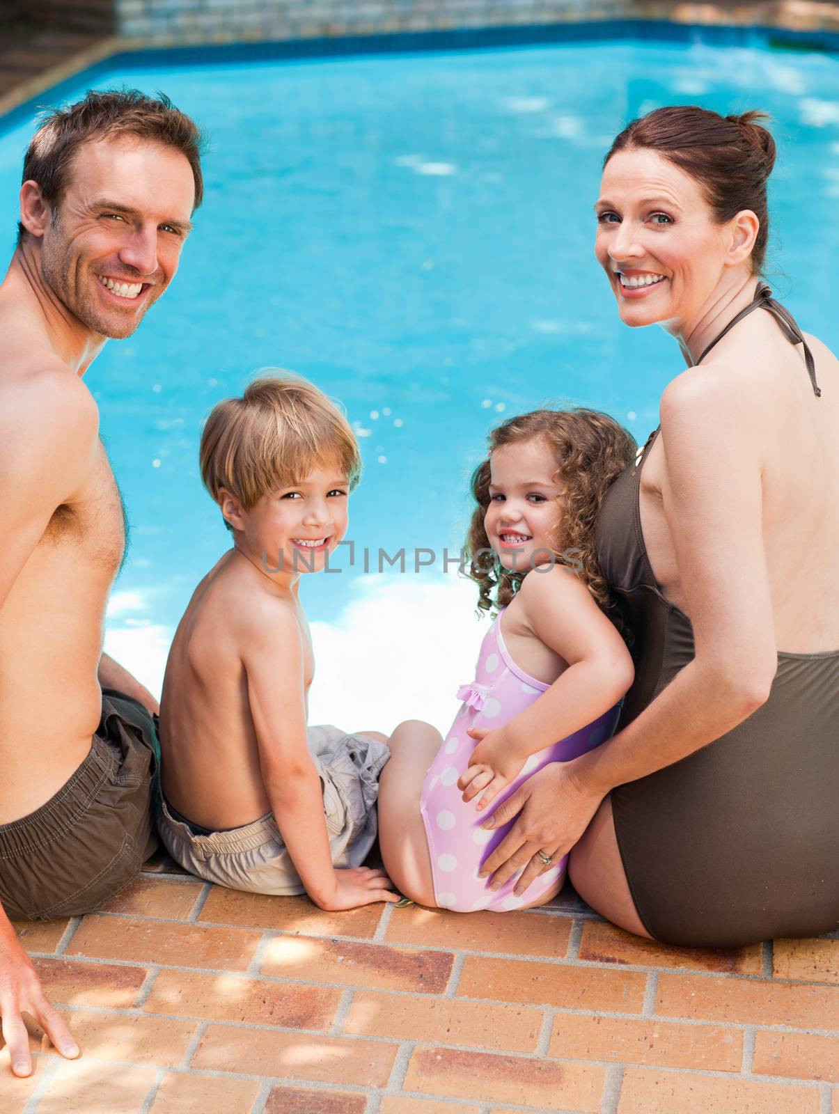 Happy family beside the swimming pool by Wavebreakmedia