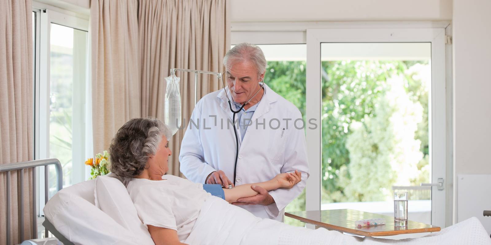 Senior doctor taking the blood pressure of his patient by Wavebreakmedia