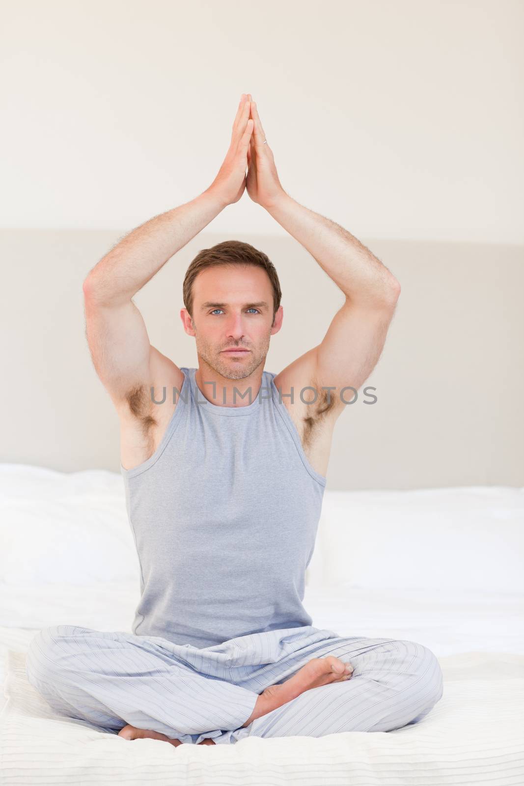 Man practicing yoga on his bed by Wavebreakmedia