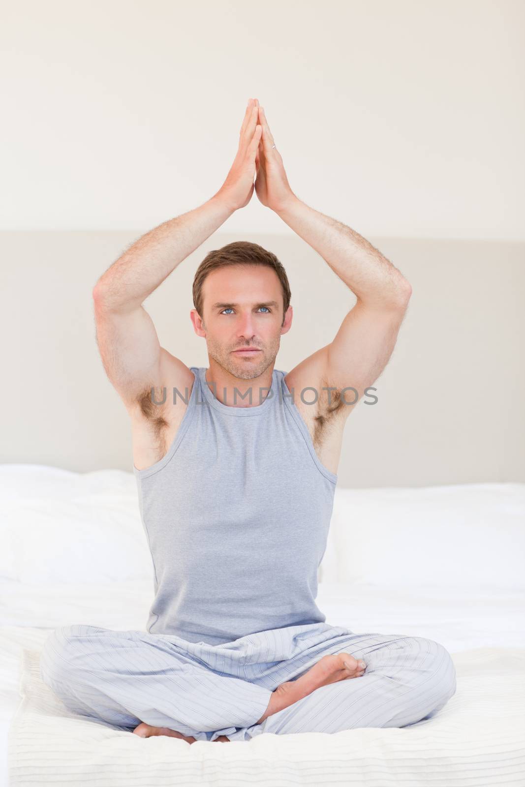 Man practicing yoga on his bed by Wavebreakmedia