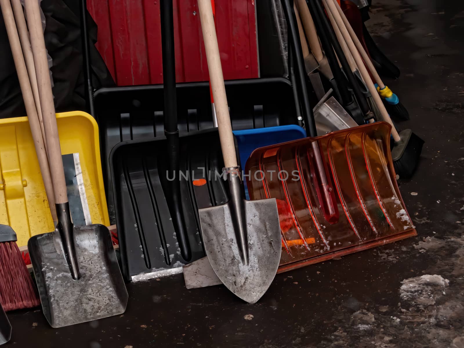 Many different tools for winter snow removal. Shovels of different shapes and brooms are in the corner. Household tool.