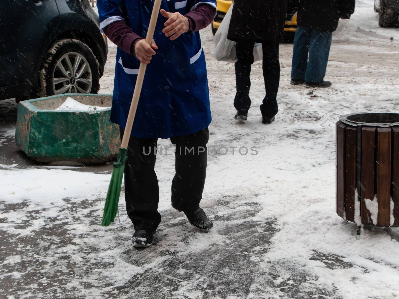 Worker janitor from the municipal service of the city cleans the snow from the sidewalk after a snowstorm on a winter day.