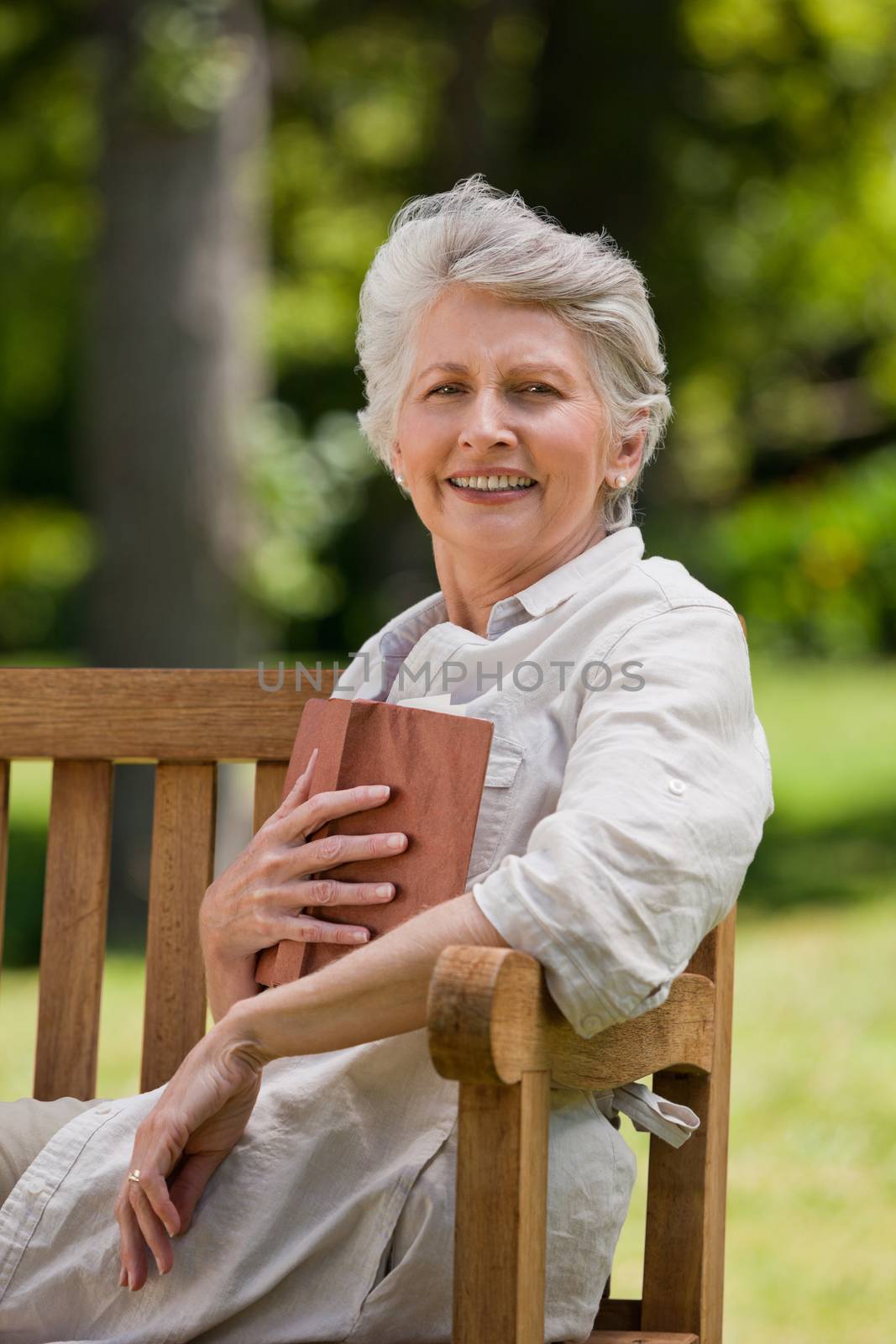Retired woman reading a book on the bench by Wavebreakmedia