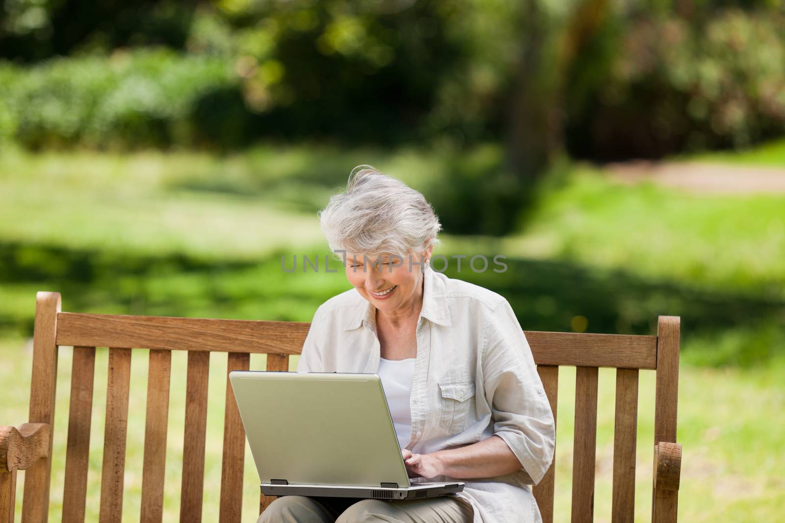 Mature woman working on her laptop on the bench by Wavebreakmedia