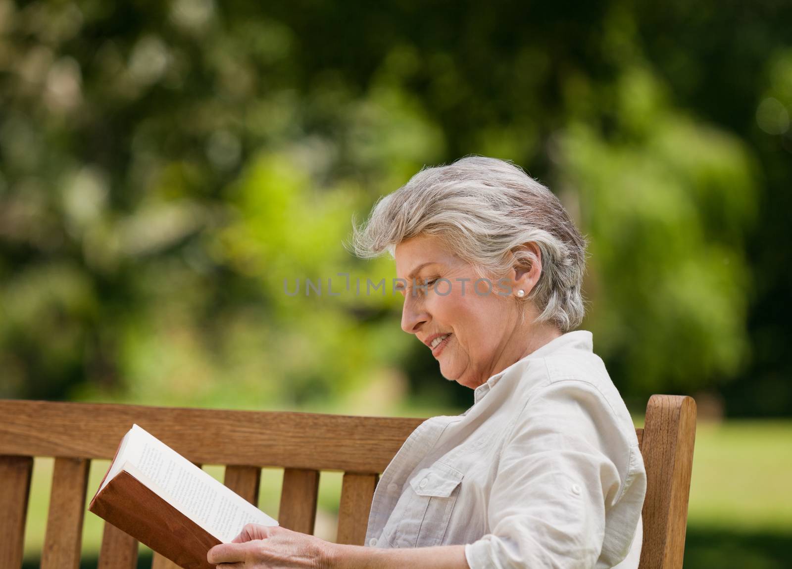 Retired woman reading a book on the bench