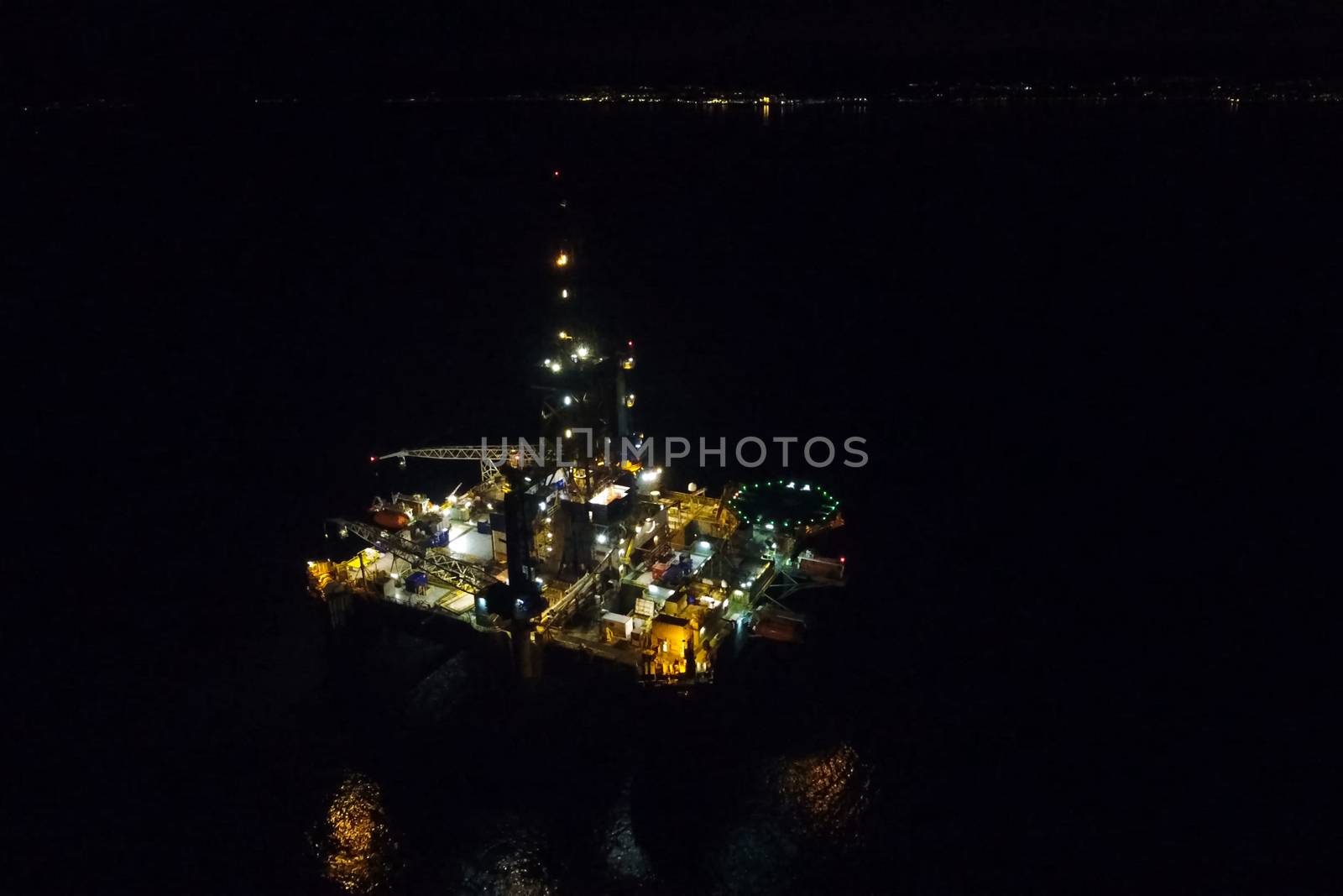 Drilling platform in the port. Oil platform at night in the light of its own lighting. Towing of the oil platform.