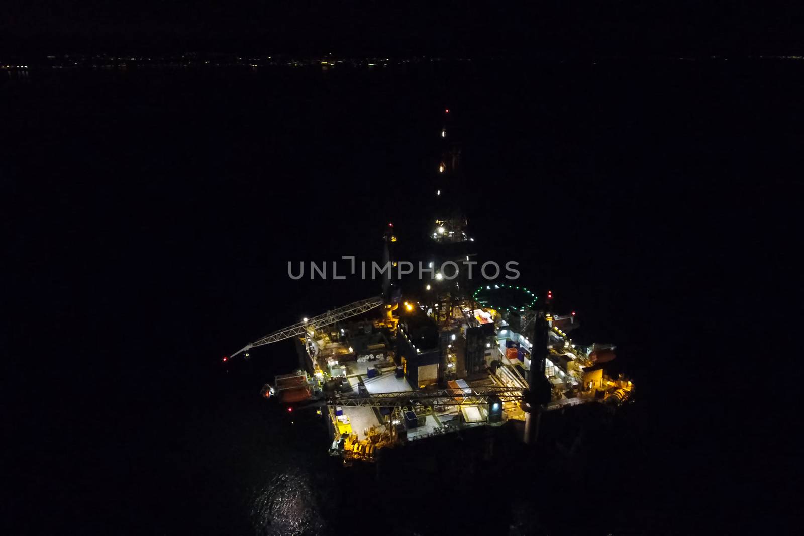 Drilling platform in the port. Oil platform at night in the light of its own lighting. Towing of the oil platform.