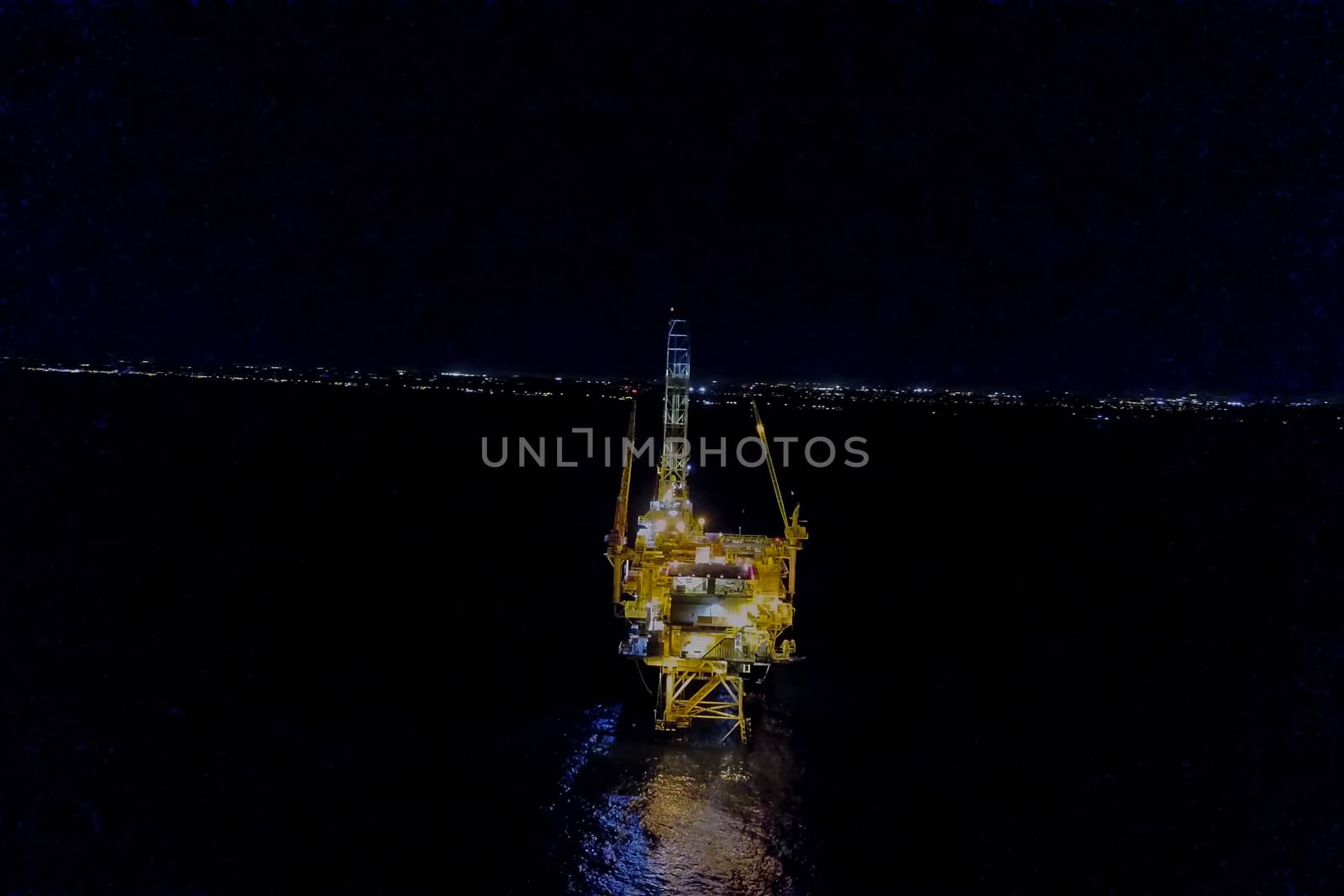 Drilling platform in the port. Oil platform at night in the light of its own lighting. Towing of the oil platform.