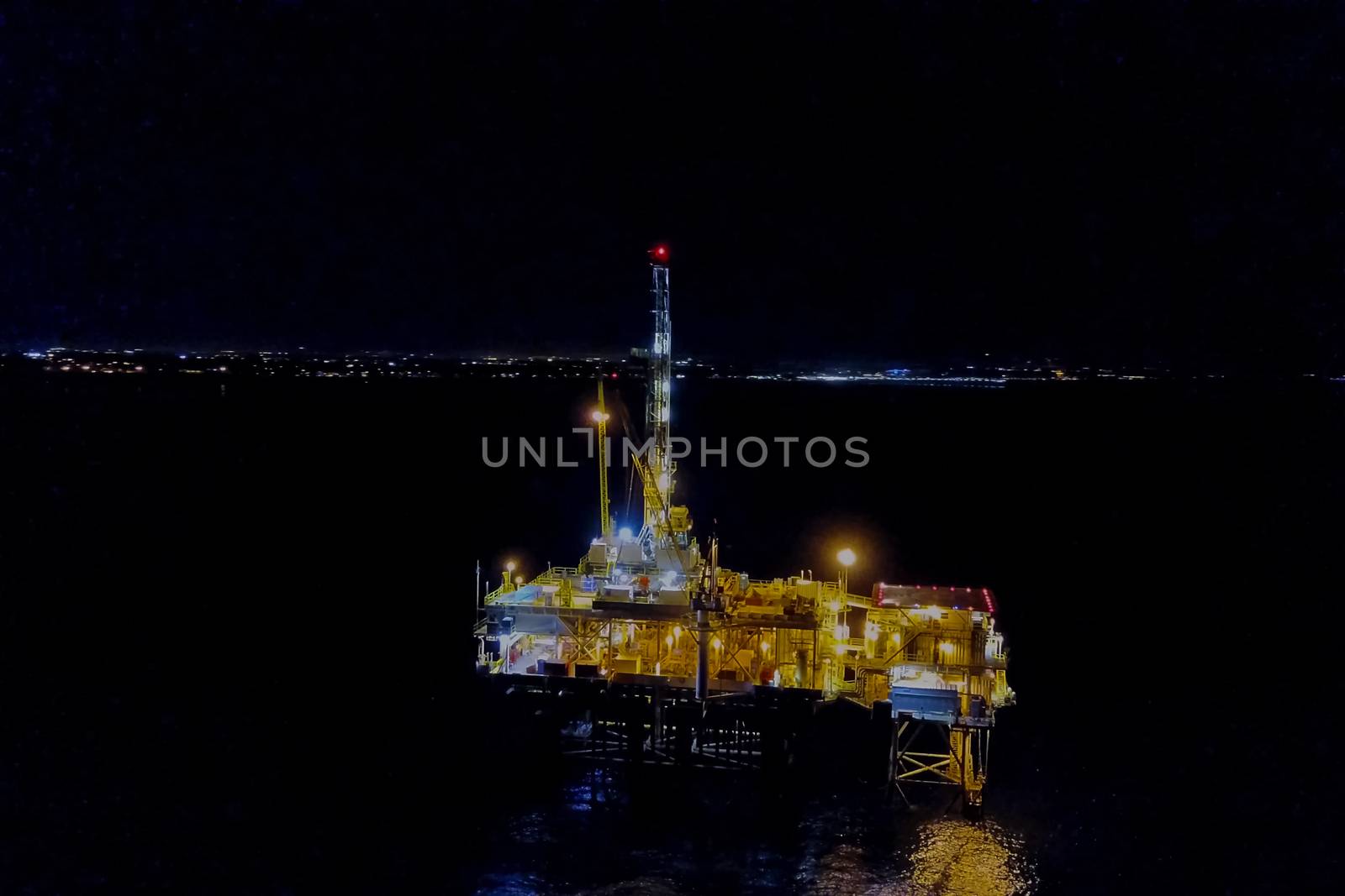 Drilling platform in the port. Oil platform at night in the light of its own lighting. Towing of the oil platform.