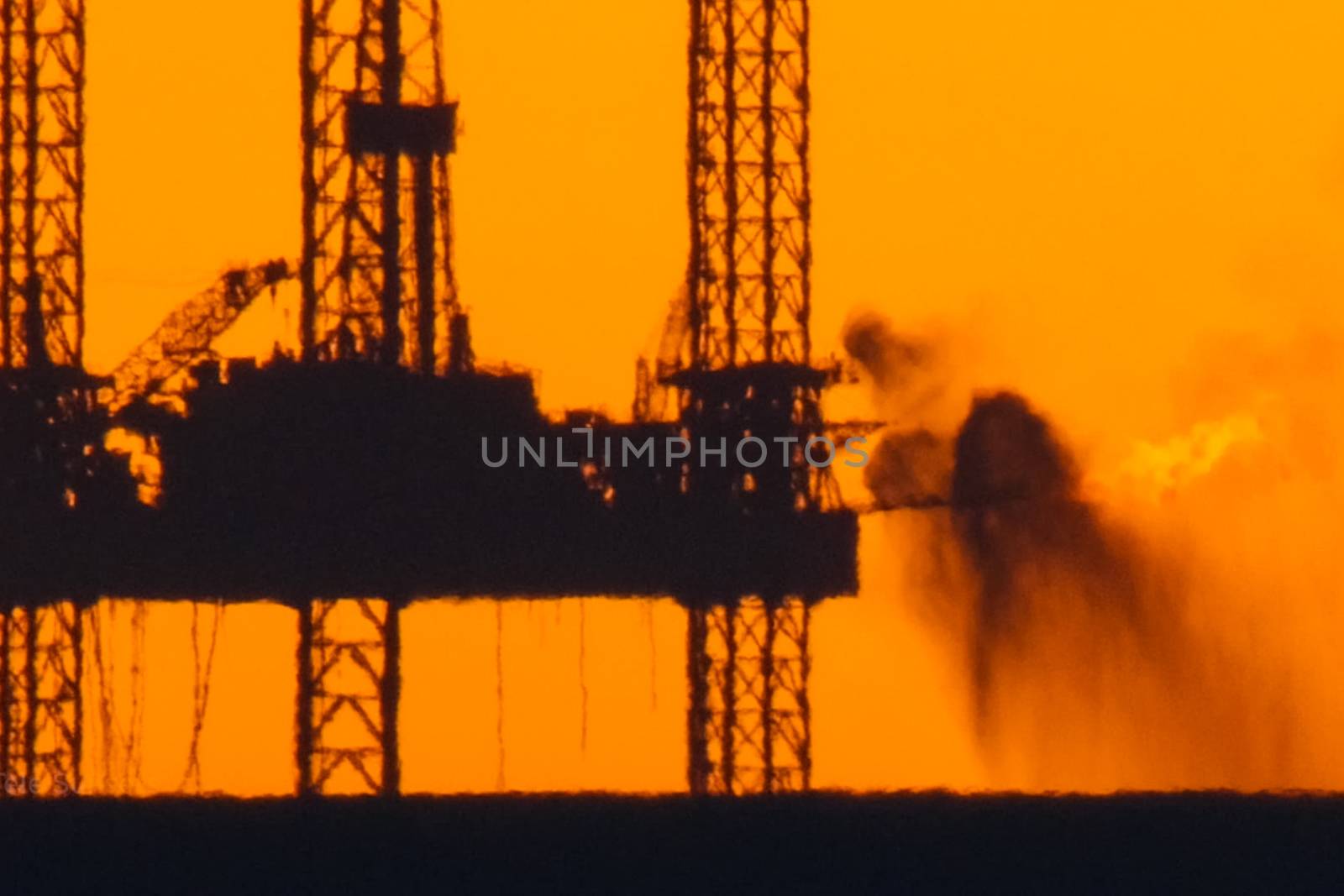 Drilling platform in the port. Oil platform at sunset with a burning torch. Towing of the oil platform.